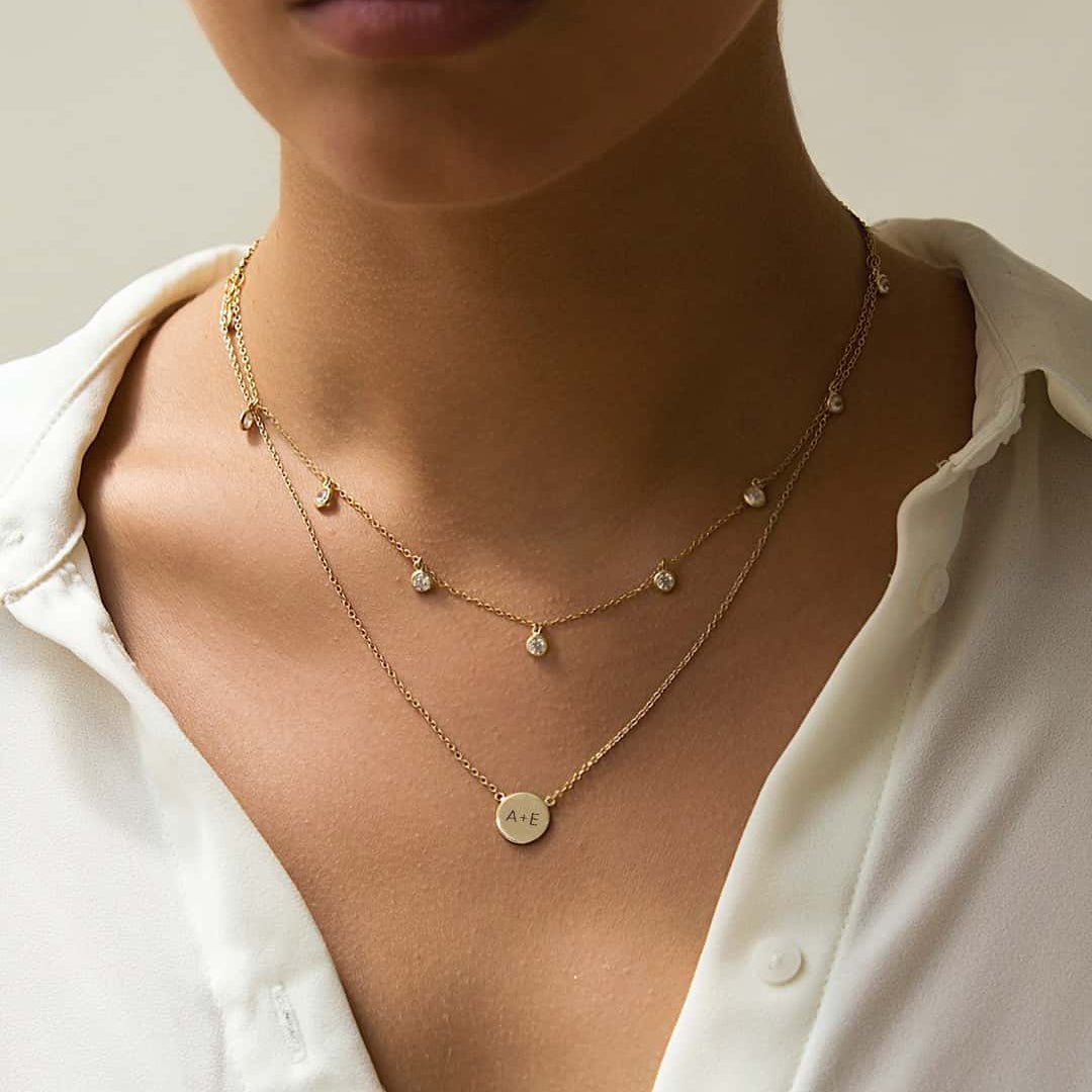 Gold vermeil engravable disc necklace engraved with initials, layered with a clear-stone chain on a model