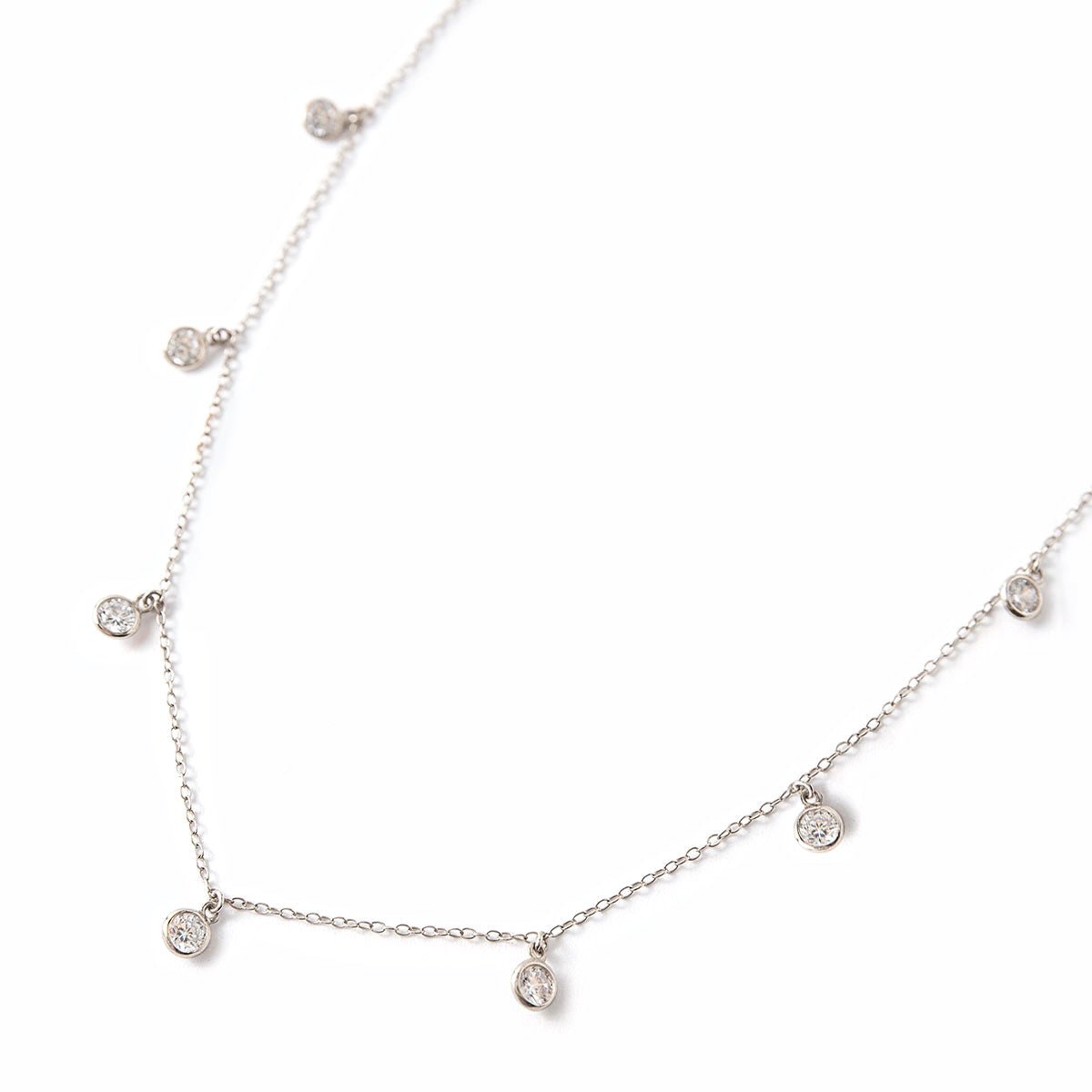 Sterling silver choker chain with dangling clear bezel stones, laid on a white background