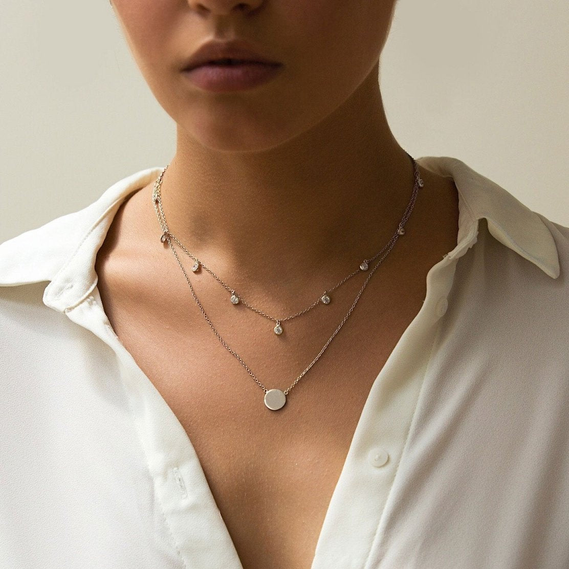 Sterling silver dangling clear stone choker, shown layered on a model's neckline