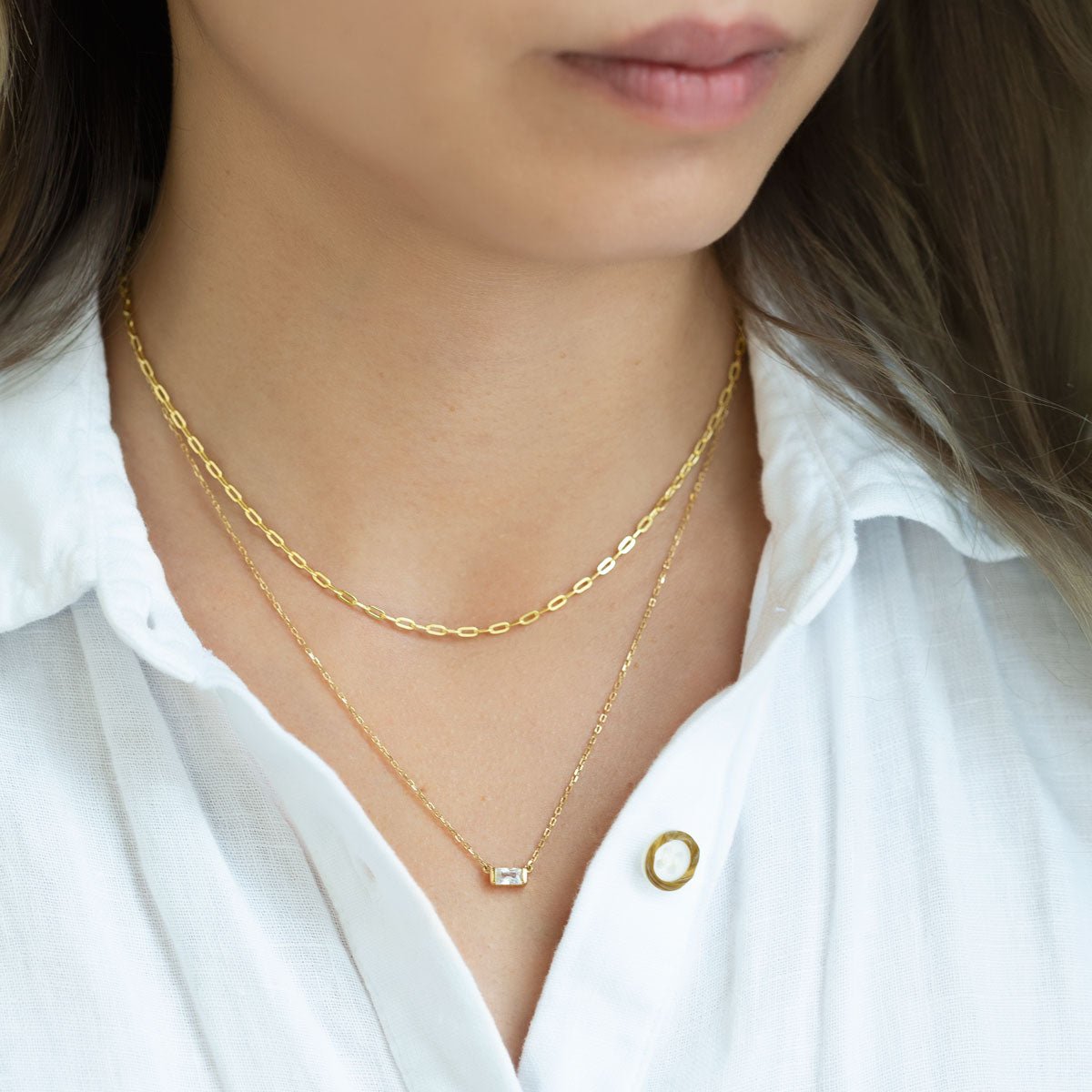 Gold vermeil paperclip chain layered with a clear crystal pendant chain, shown on a model's neckline