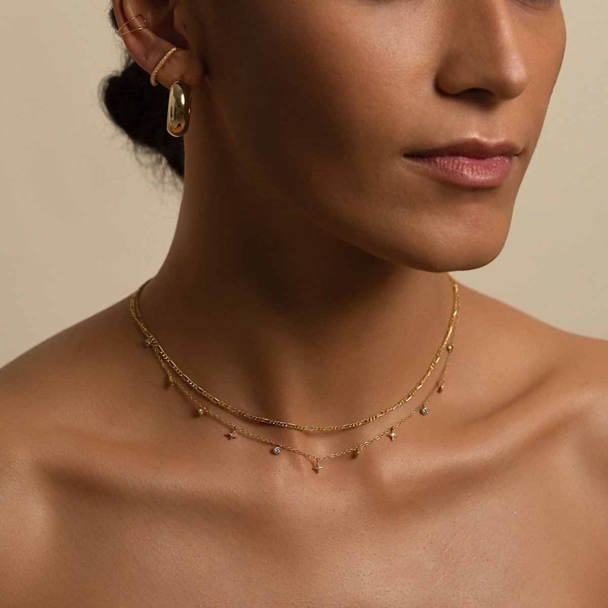 Gold vermeil Figaro chain necklace layered with a charm chain, shown on a model's neckline