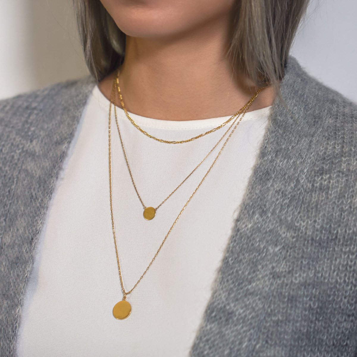 Gold vermeil Figaro disc trio necklace layered with disc pendants, shown on a model in a cardigan