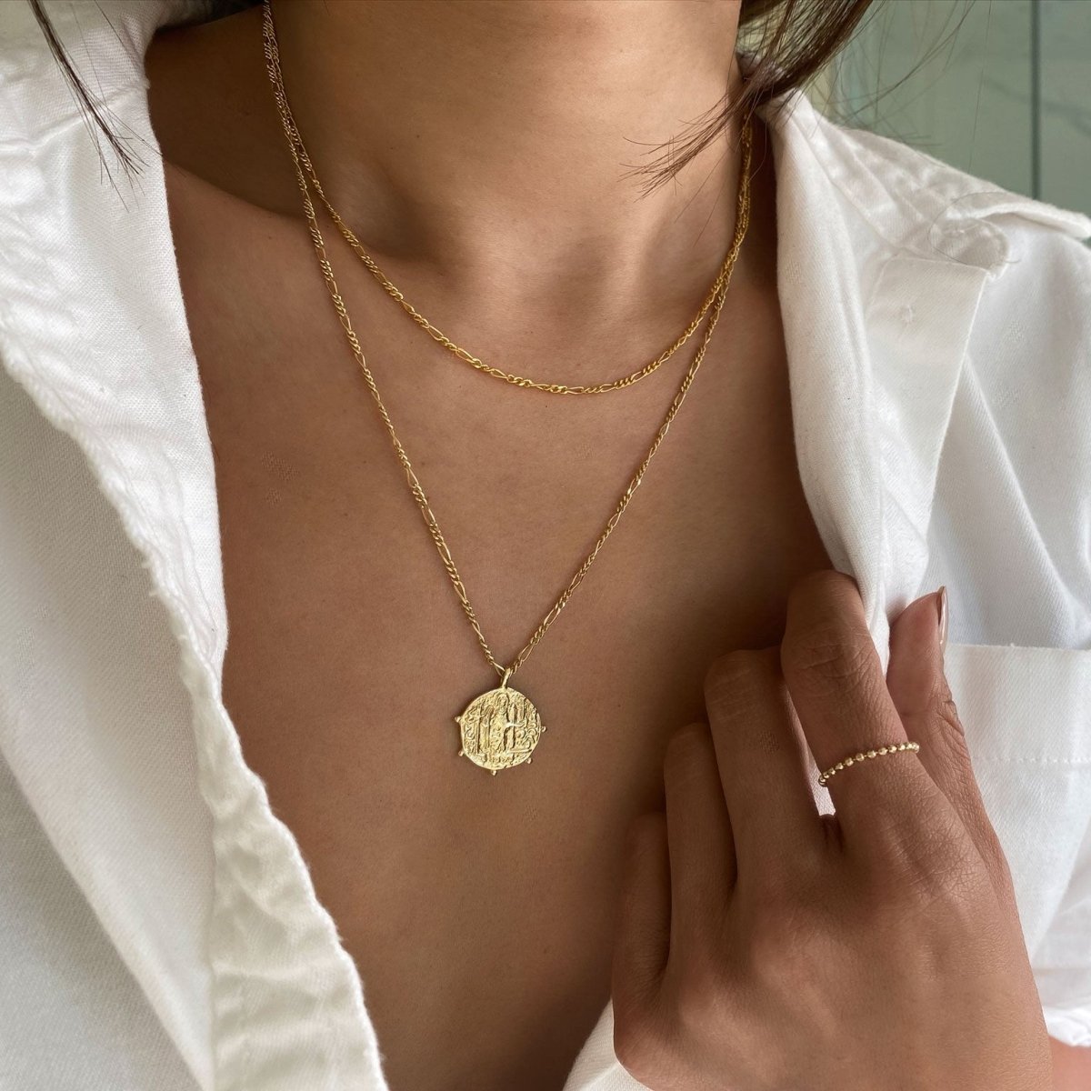 Gold vermeil figaro chain and coin pendant necklace duo shown layered on a model's neckline