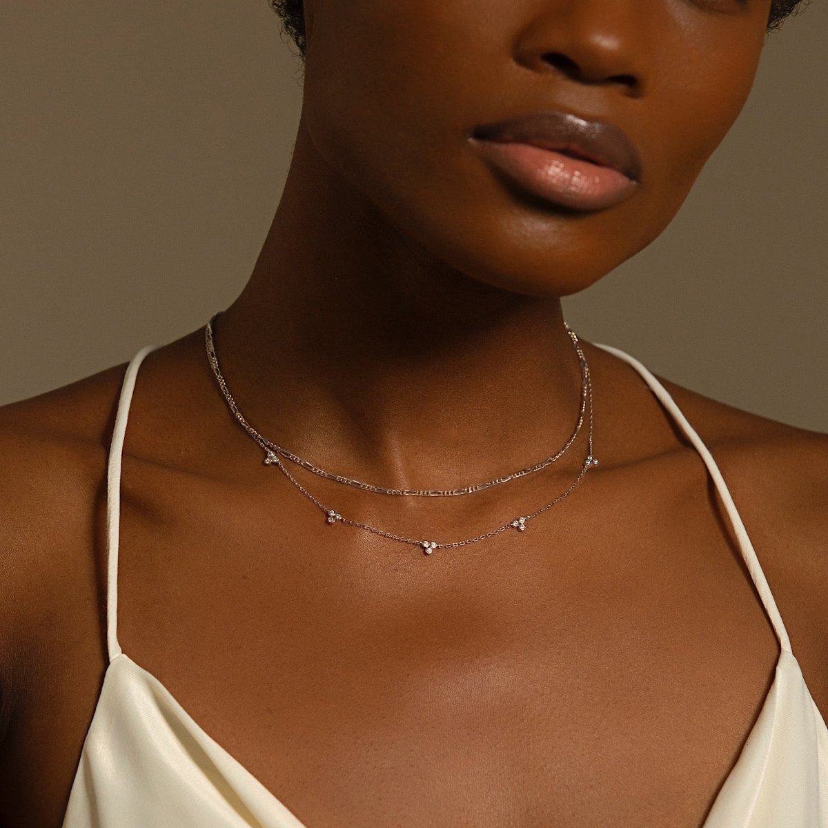Sterling silver necklace with clear-stone clover clusters, shown layered on a model's neckline