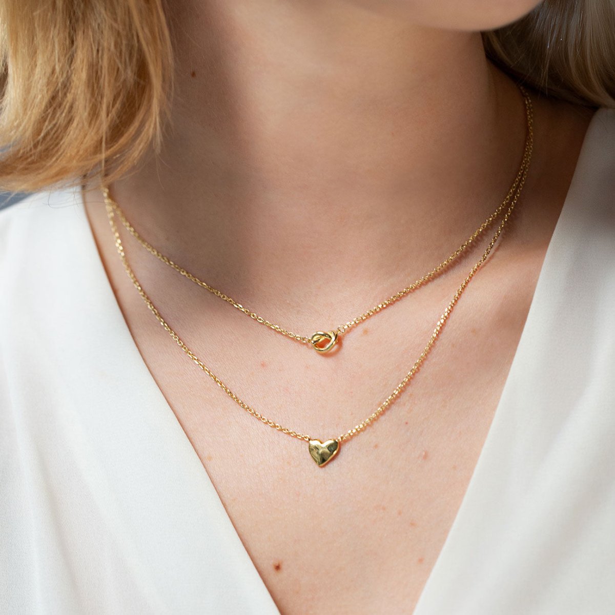 Gold vermeil puffed heart pendant on a fine chain, shown layered on a model's neckline