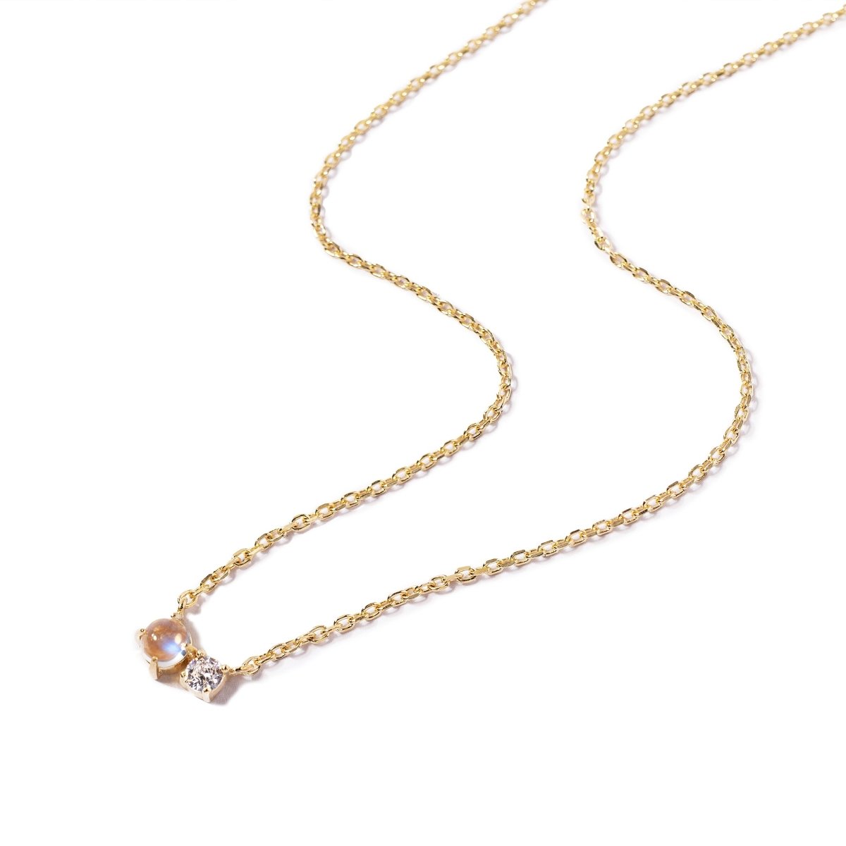 Gold vermeil duet necklace with a moonstone and a small clear stone on a fine chain, on a white background