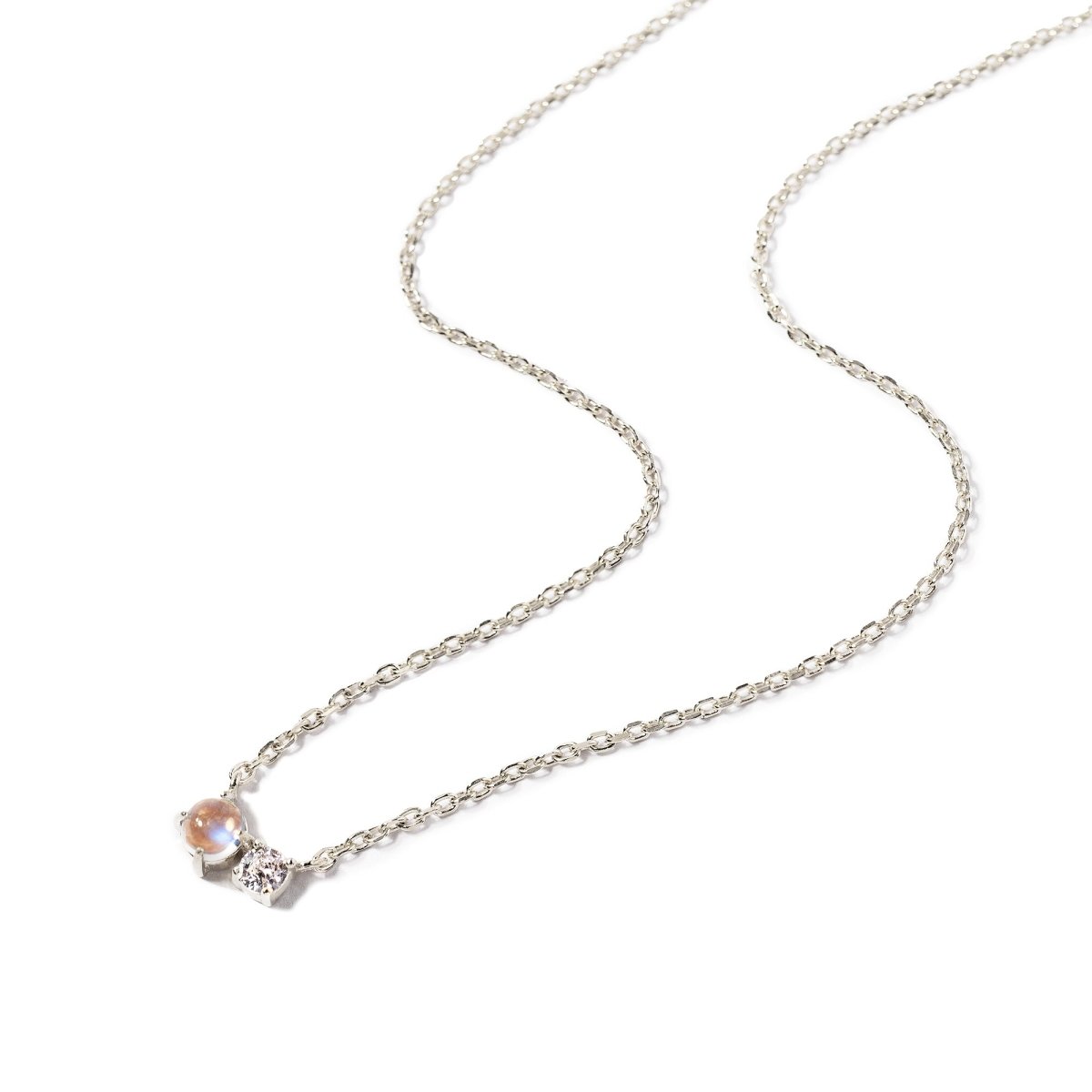 Sterling silver duet necklace with a moonstone and a small clear stone on a fine chain, on a white background