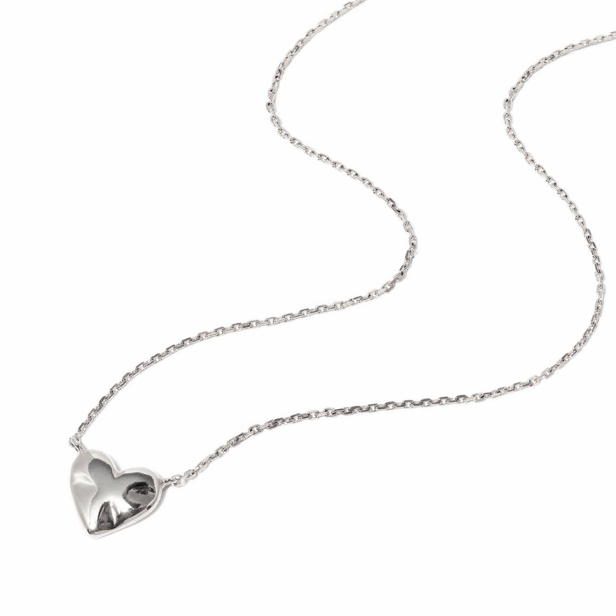 Sterling silver puffed heart pendant on a fine cable chain, laid on a white background