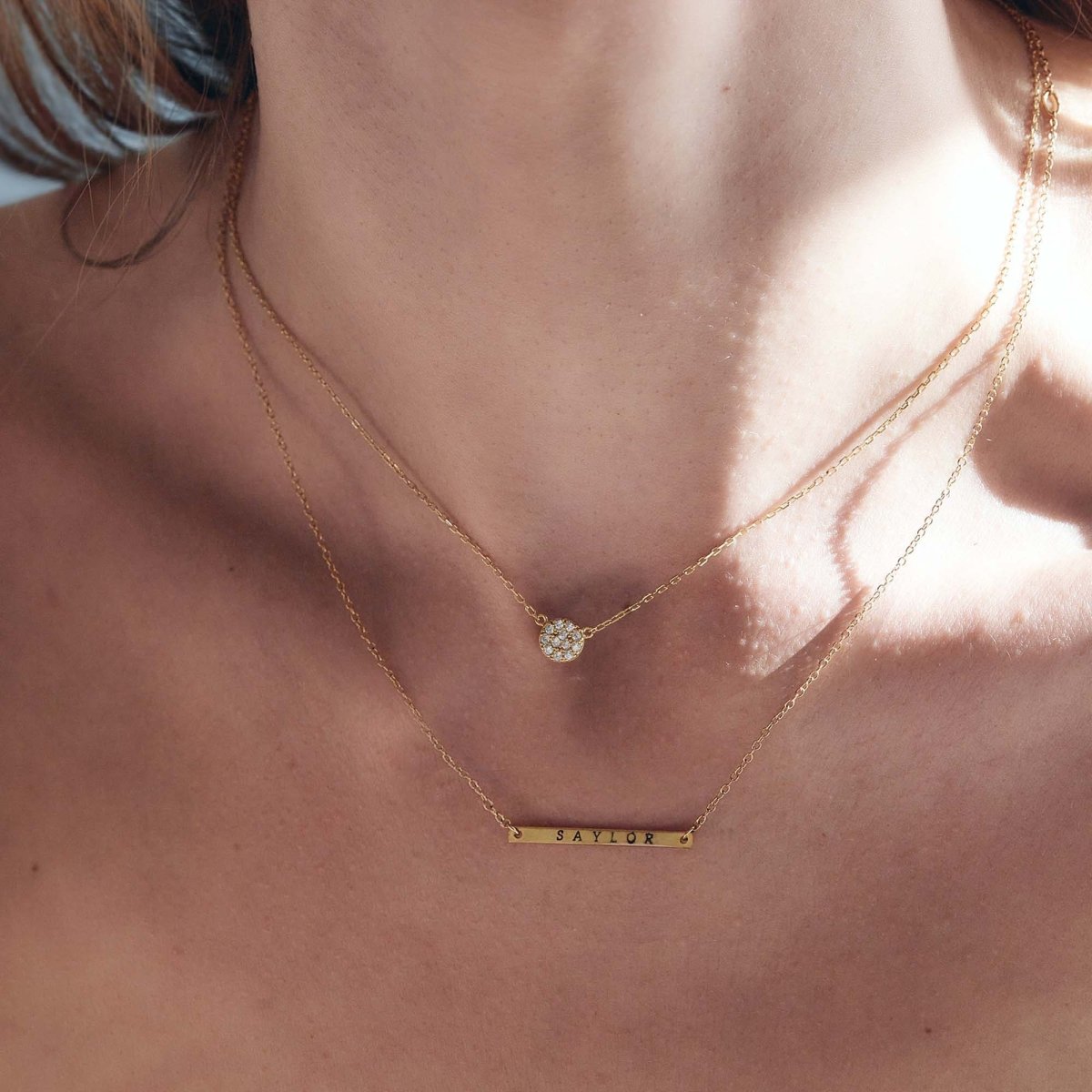 Gold vermeil white zirconia pavé disc necklace layered above an engraved name bar on a model