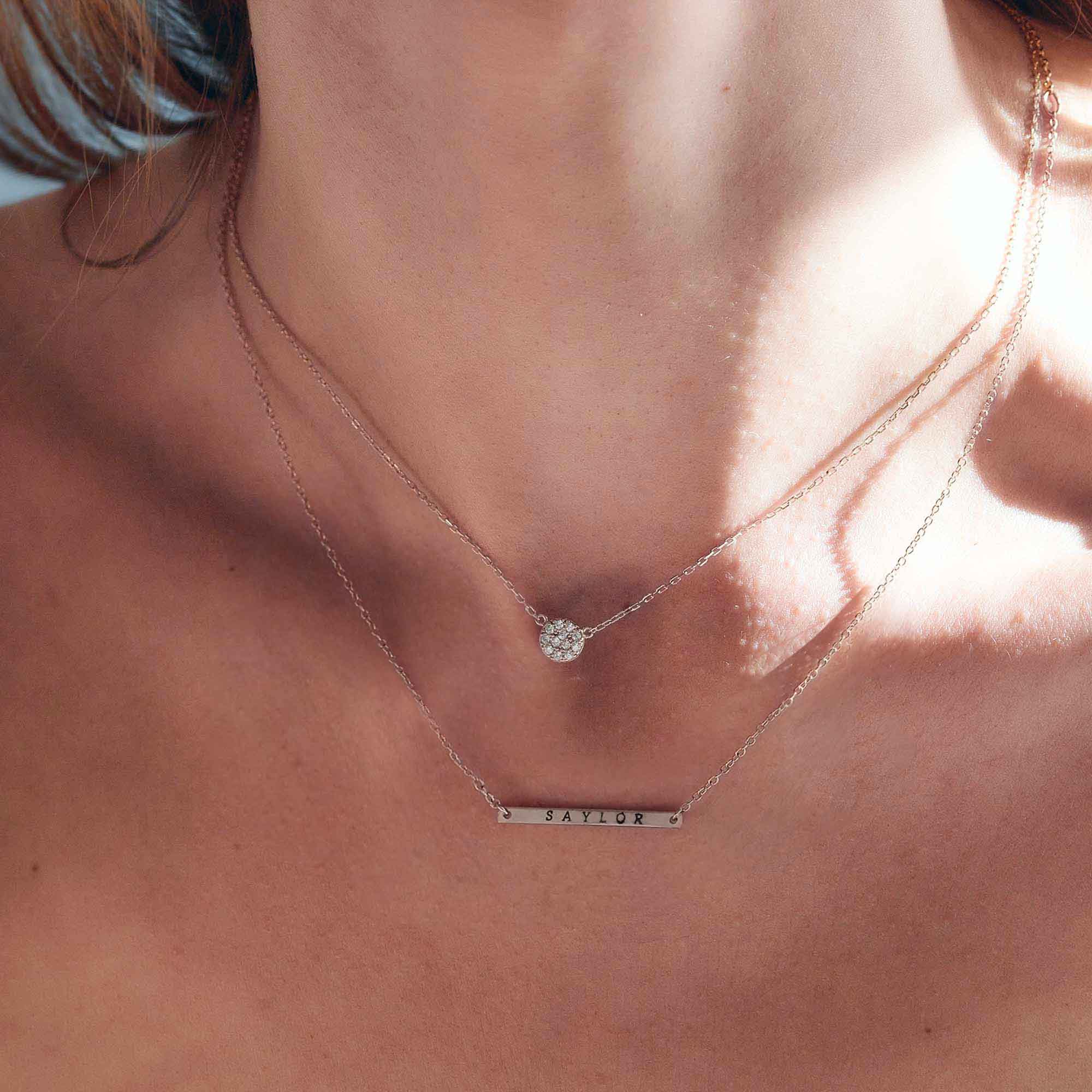 Sterling silver white zirconia pavé disc necklace layered with a bar necklace on a model