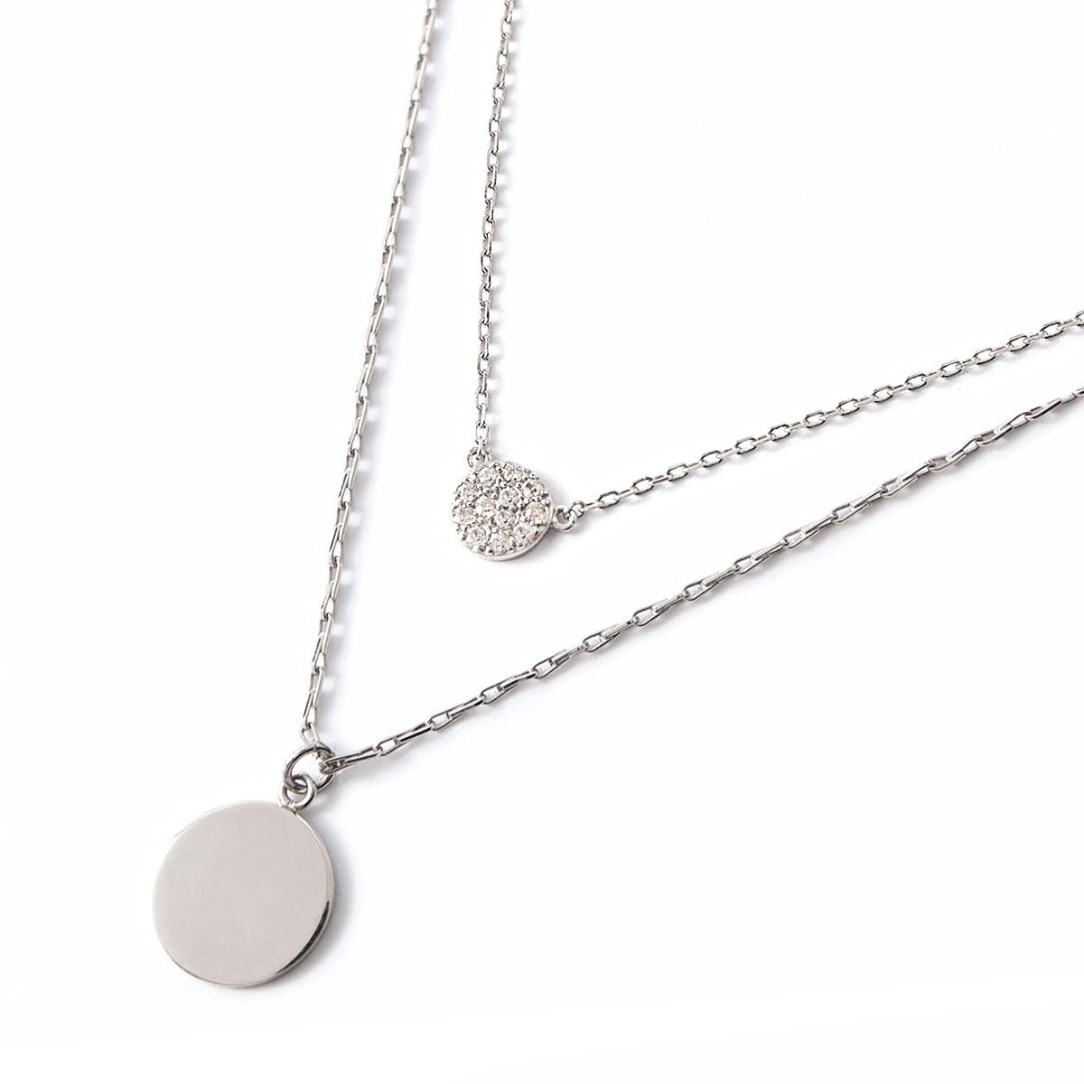 Sterling silver layered necklace duo with a plain disc and a round zirconia pavé disc, on a white background