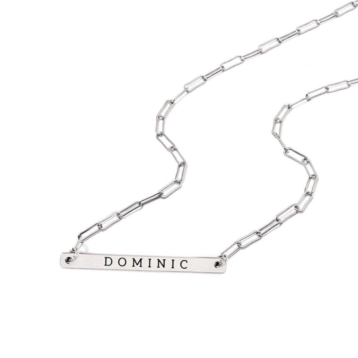 Sterling silver paperclip chain necklace with a thin bar pendant engraved with a name, on a white background