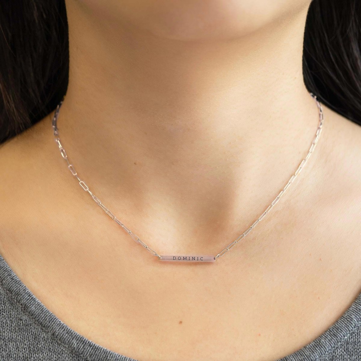 Gold-filled thin bar necklace engraved with a name, shown close on a model's neckline