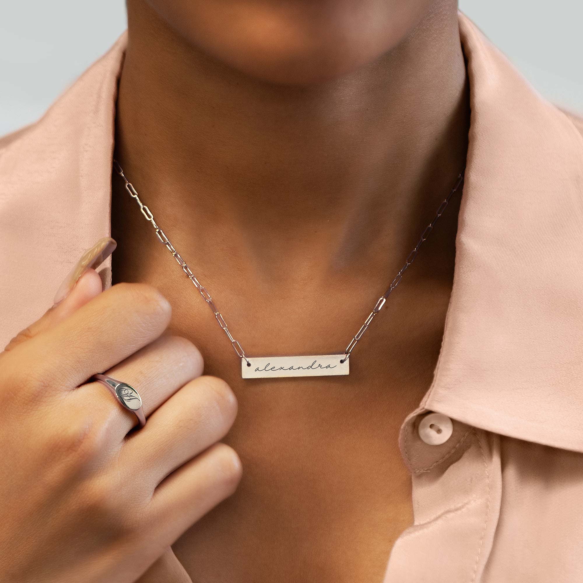 Sterling silver engravable bar necklace engraved with a name, shown on a model's neckline