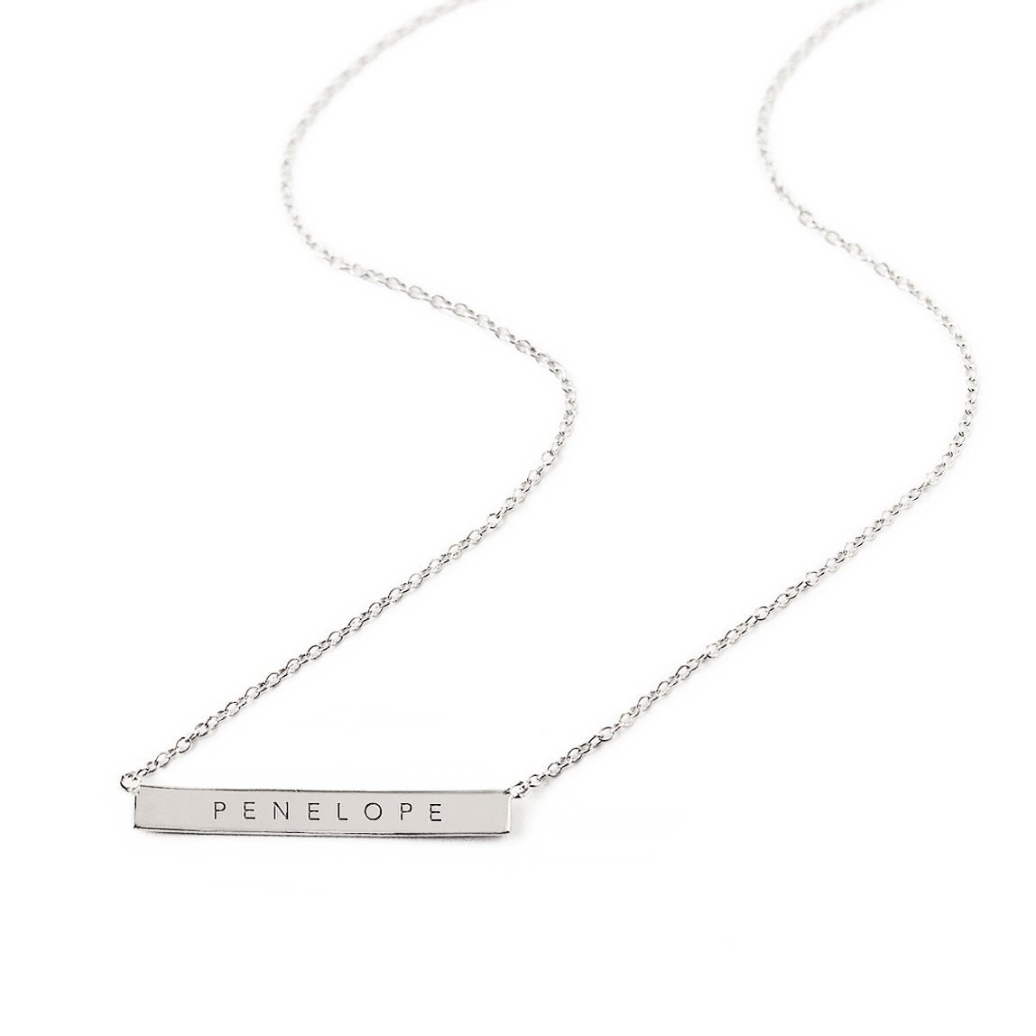 Sterling silver bar necklace engraved with a name on a thin cable chain, on a white background