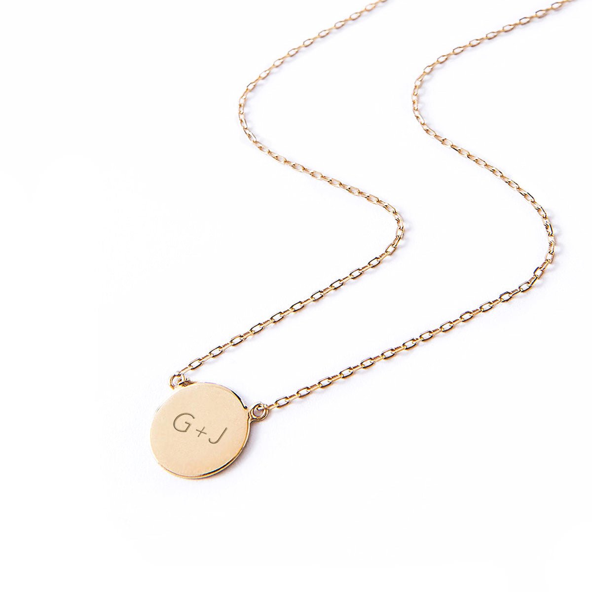 Gold vermeil engravable disc necklace engraved with initials, laid on a white background