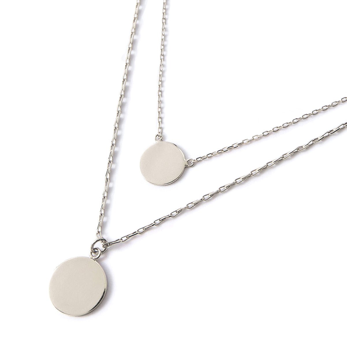 Sterling silver layered necklace duo with two plain round discs on fine chains, on a white background