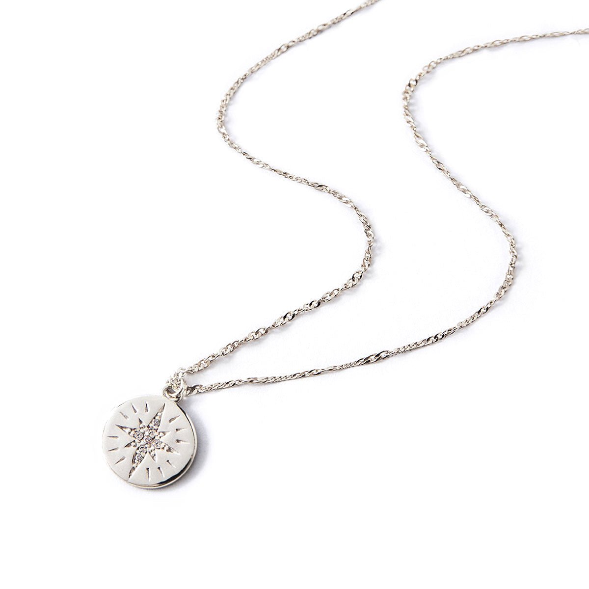 Sterling silver star disc necklace with a white zirconia starburst pendant, on a white background