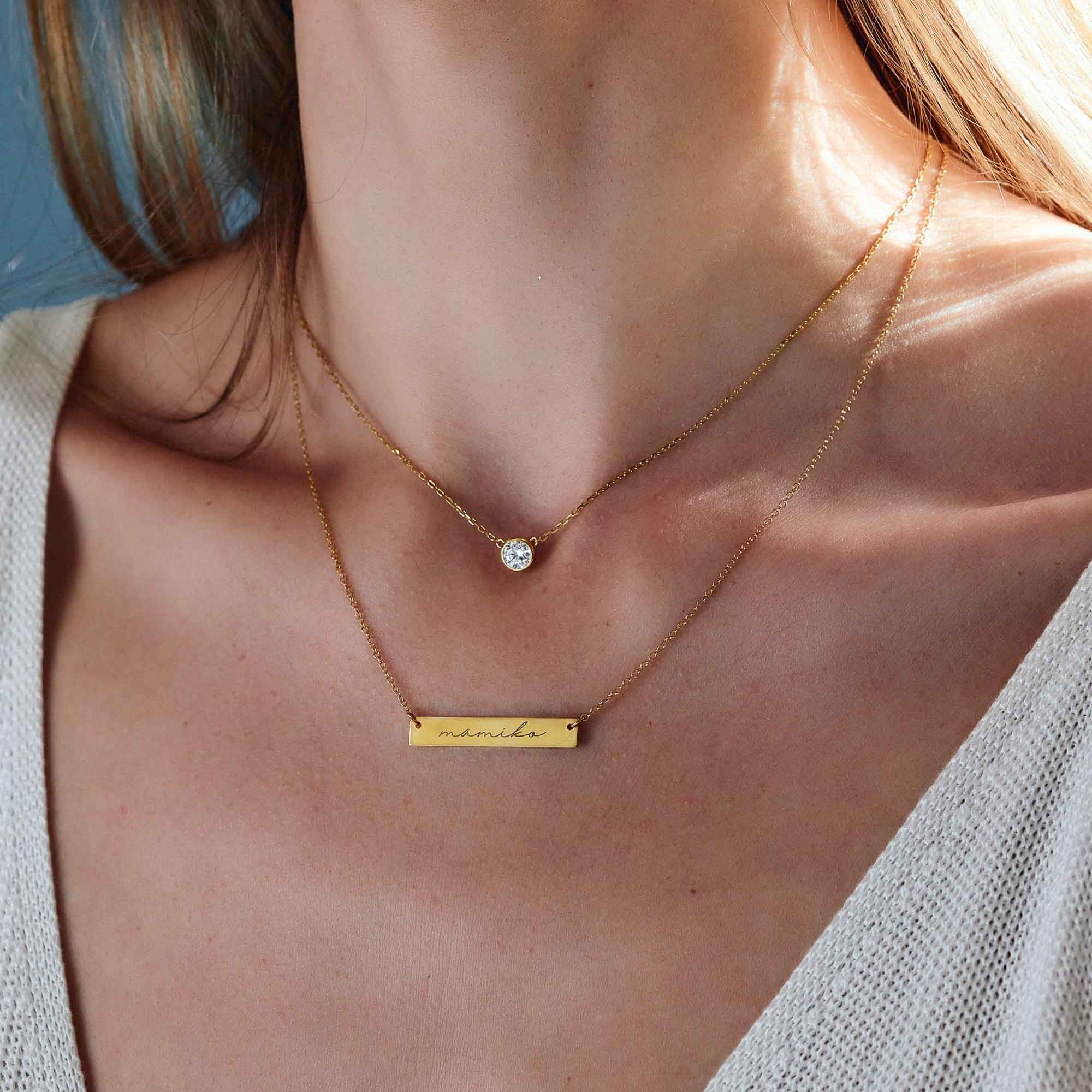 Gold vermeil name bar necklace engraved with a name, layered with a clear stone necklace on a model