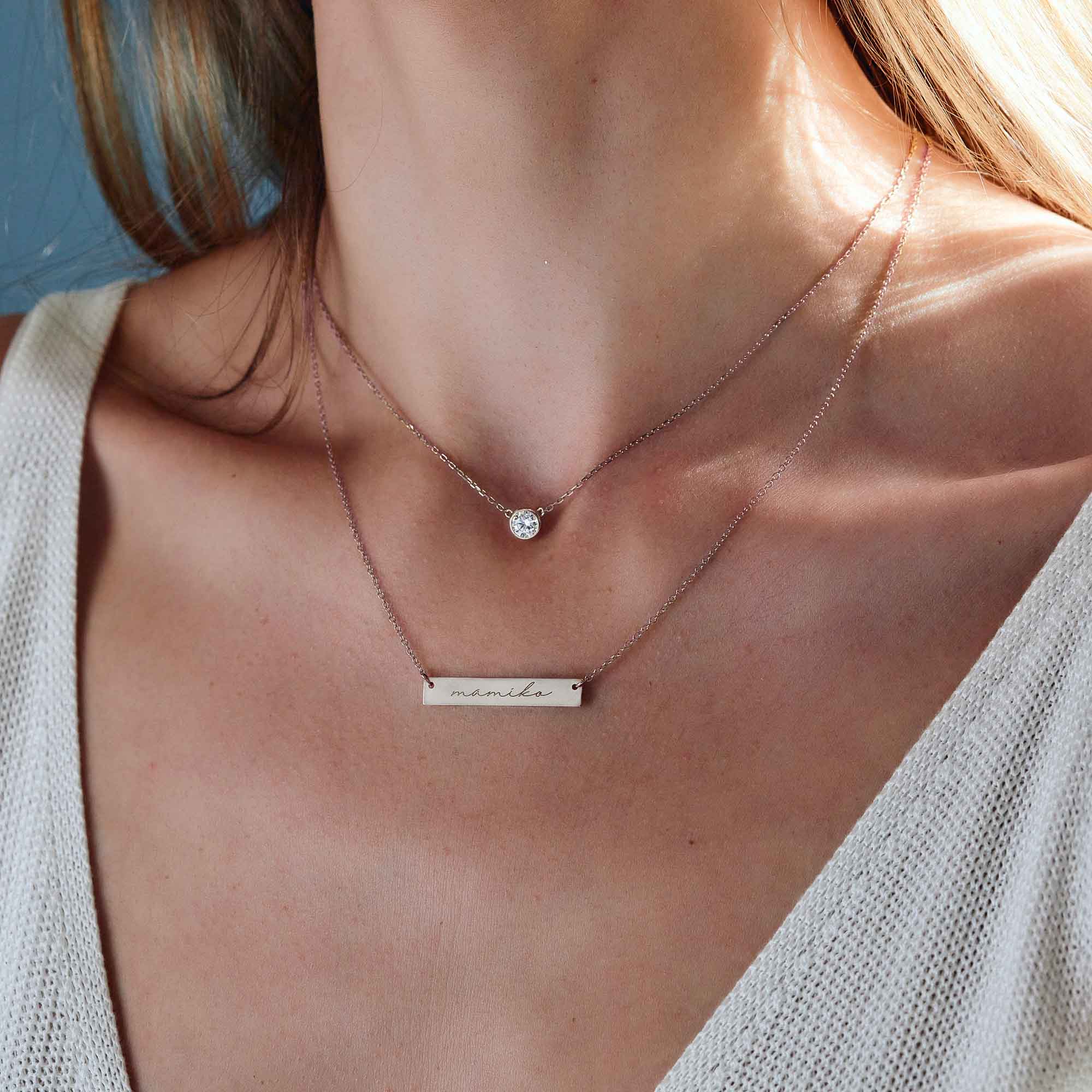 Sterling silver round zirconia solitaire necklace layered with a bar necklace engraved with a name