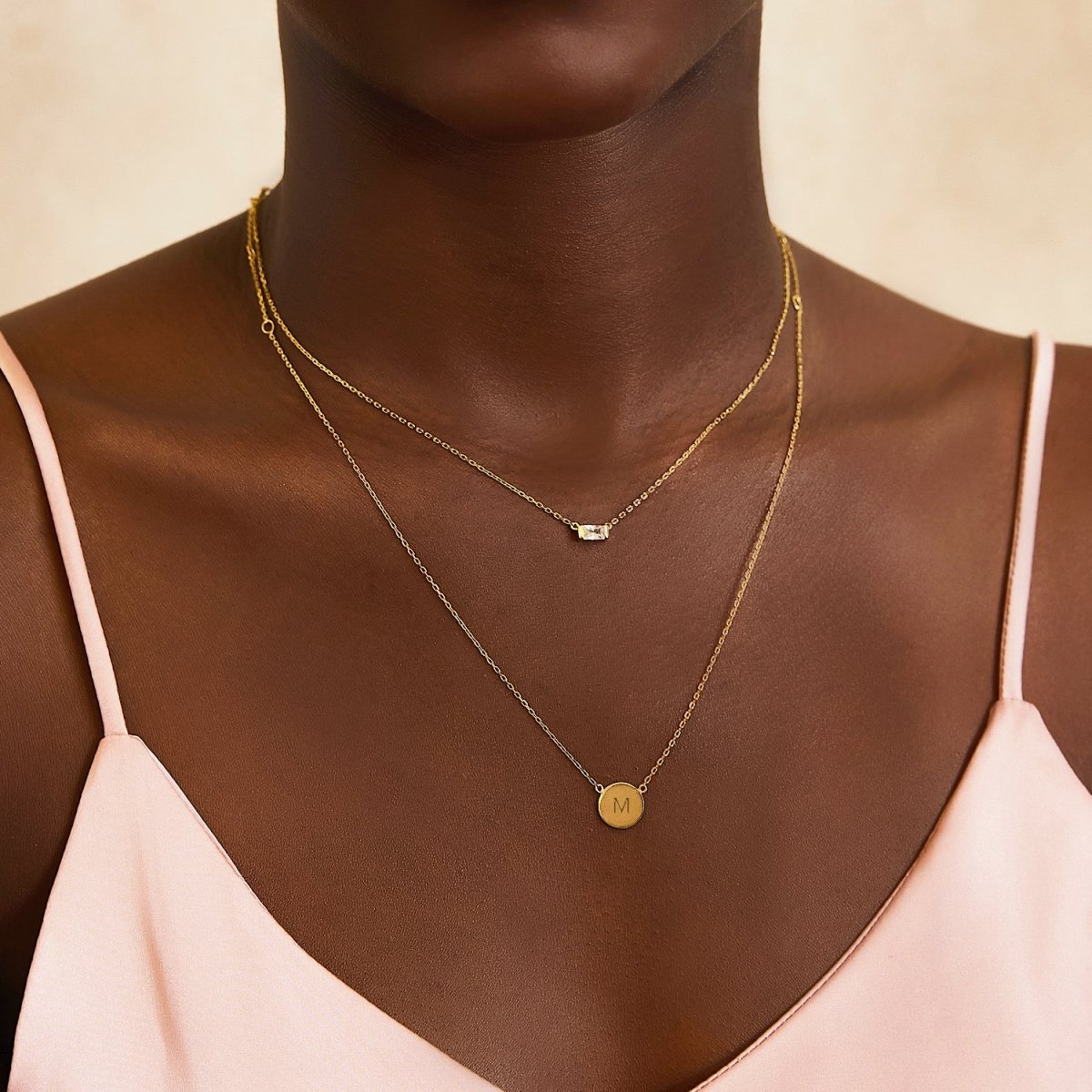 Gold vermeil initial disc necklace engraved with an initial, layered and shown on a model's neckline