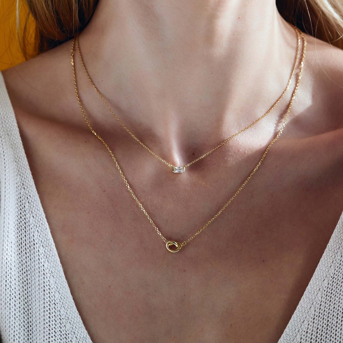 Gold vermeil baguette white zirconia and loveknot layered necklaces, shown on a model's neckline