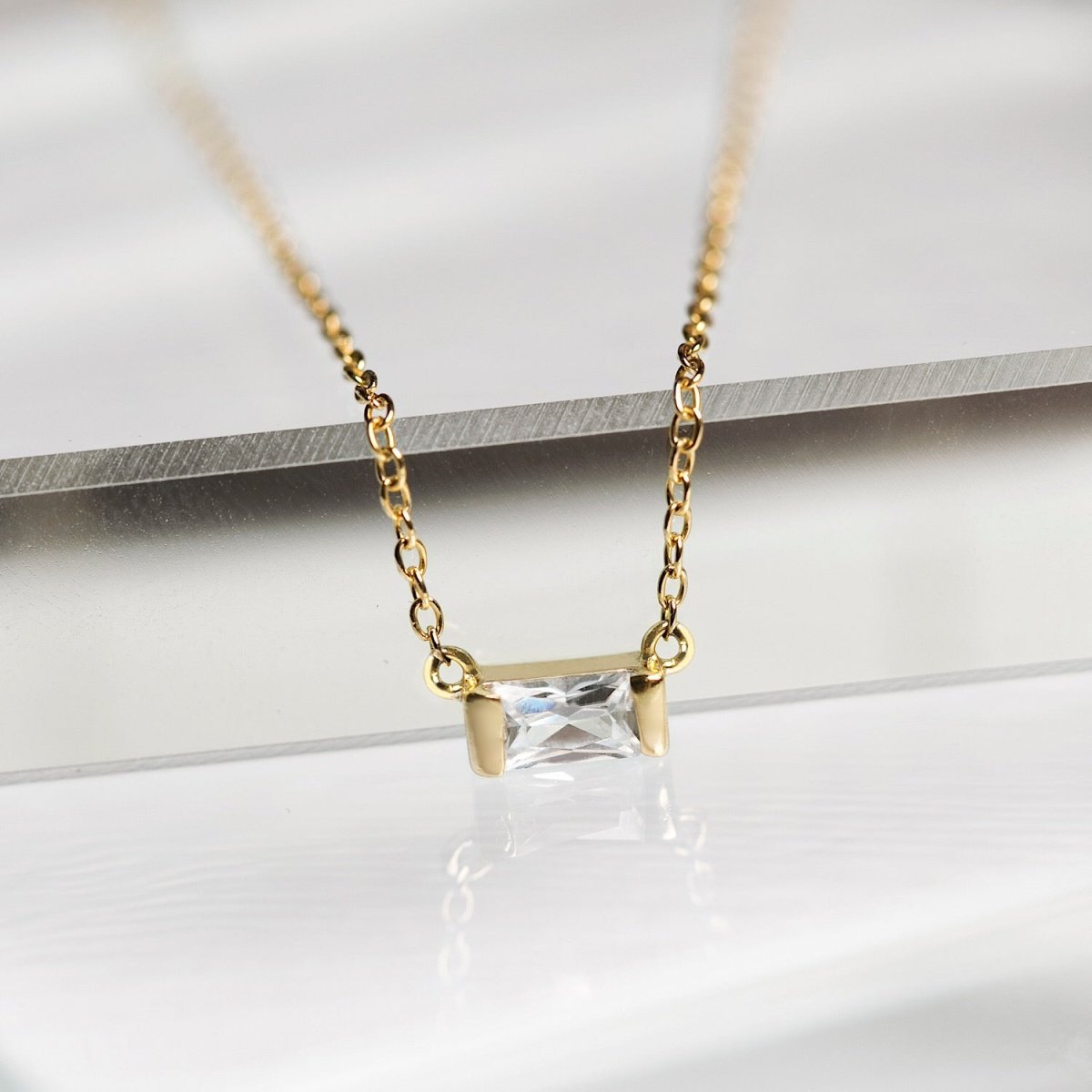 Gold vermeil baguette necklace with a clear white zirconia pendant, close-up detail