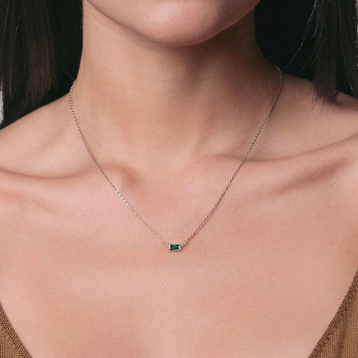 Sterling silver emerald baguette necklace on a fine chain, shown centered on a model's neckline