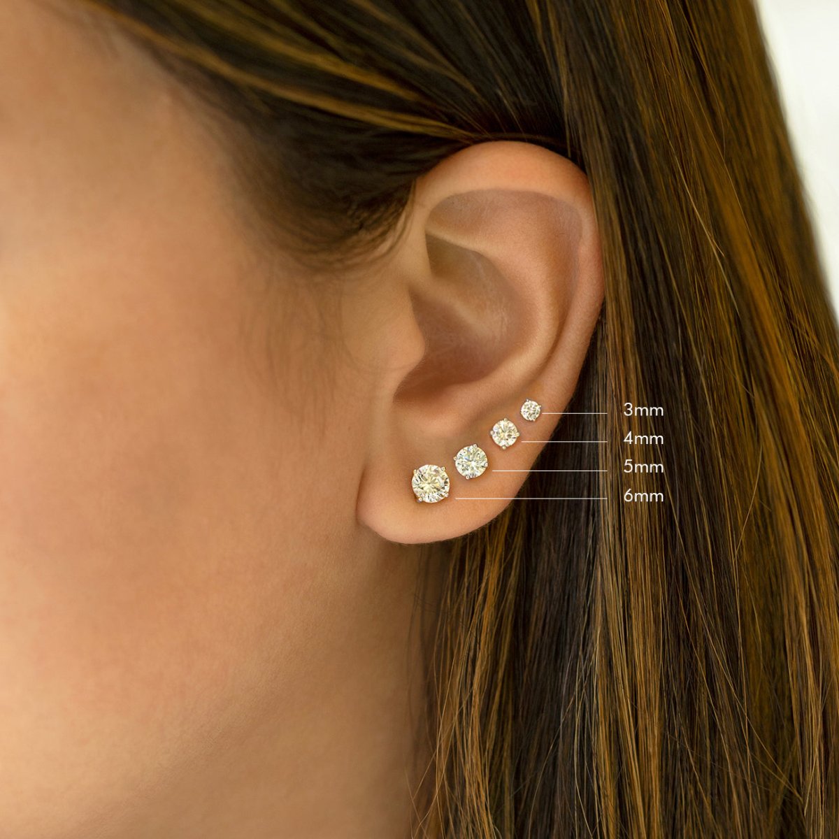 Sterling silver round zirconia studs on a model's lobe, size comparison 3mm, 4mm, 5mm and 6mm
