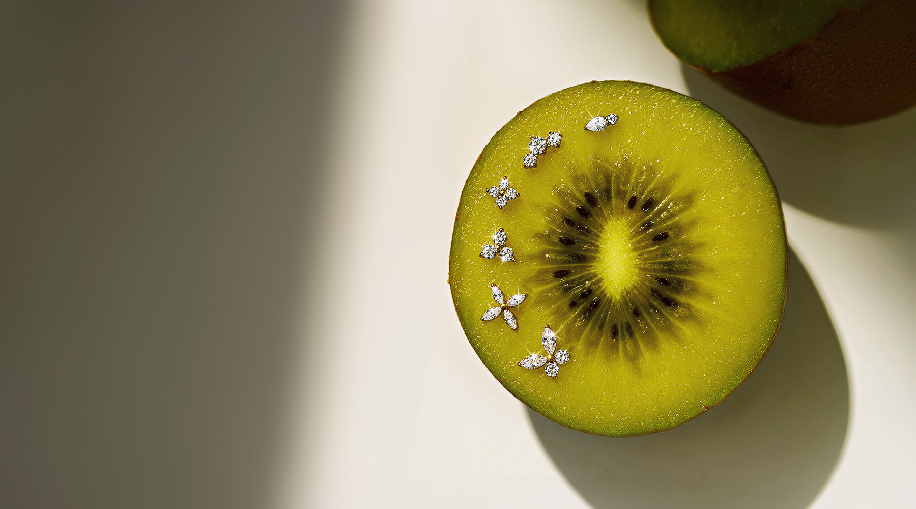 Close-up of AMYO flat back stud earrings on a sliced kiwi featuring dainty cartilage and lobe earrings for everyday wear.