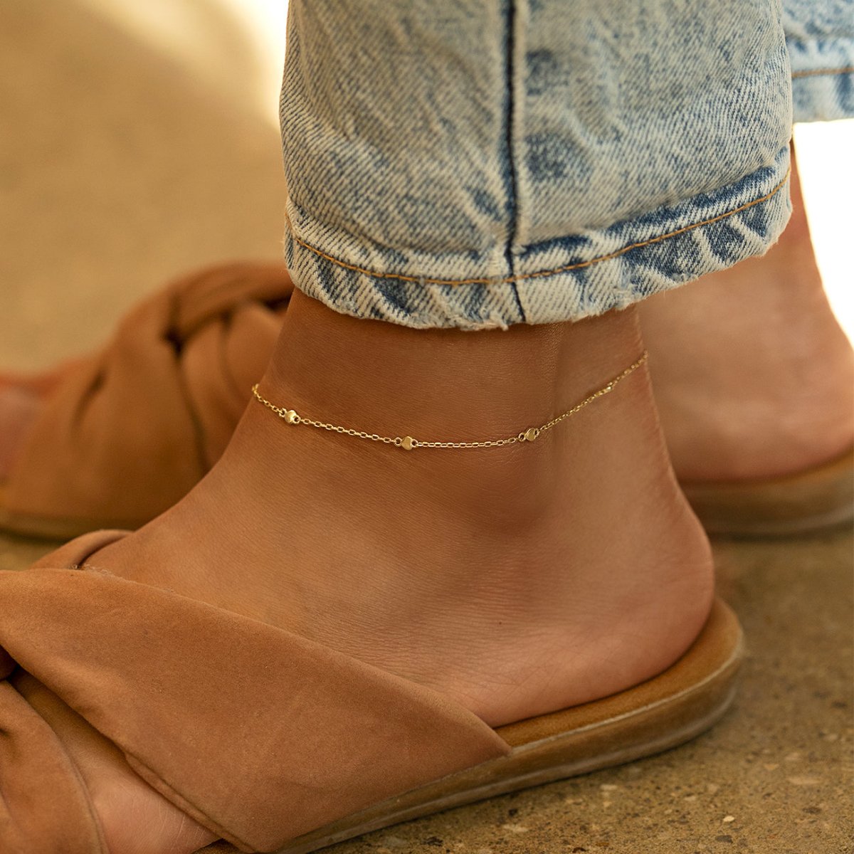 Gold vermeil heart-station chain anklet shown on a model's ankle with sandals