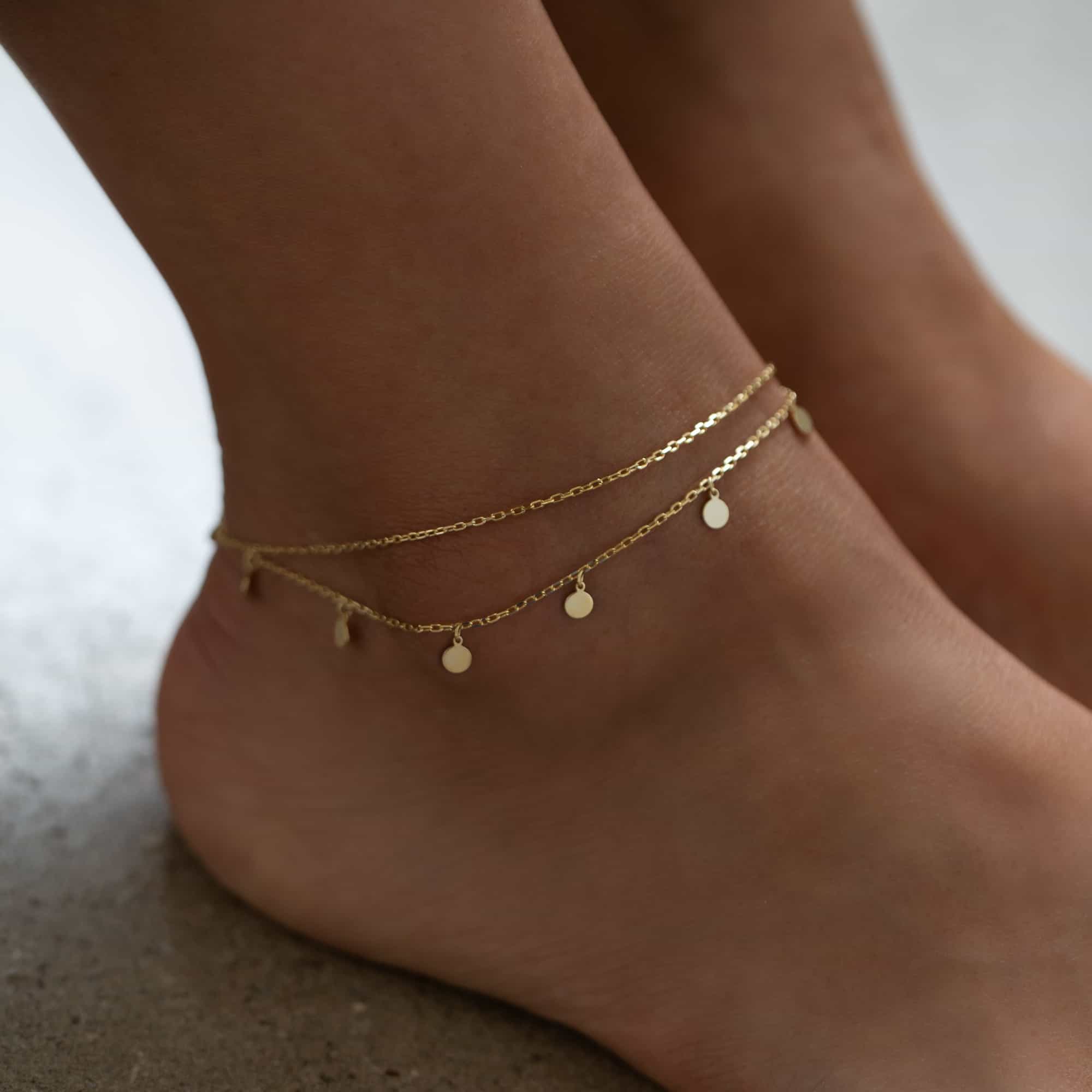 Gold vermeil layered disc anklet with dangling round charms, shown on a model's ankle