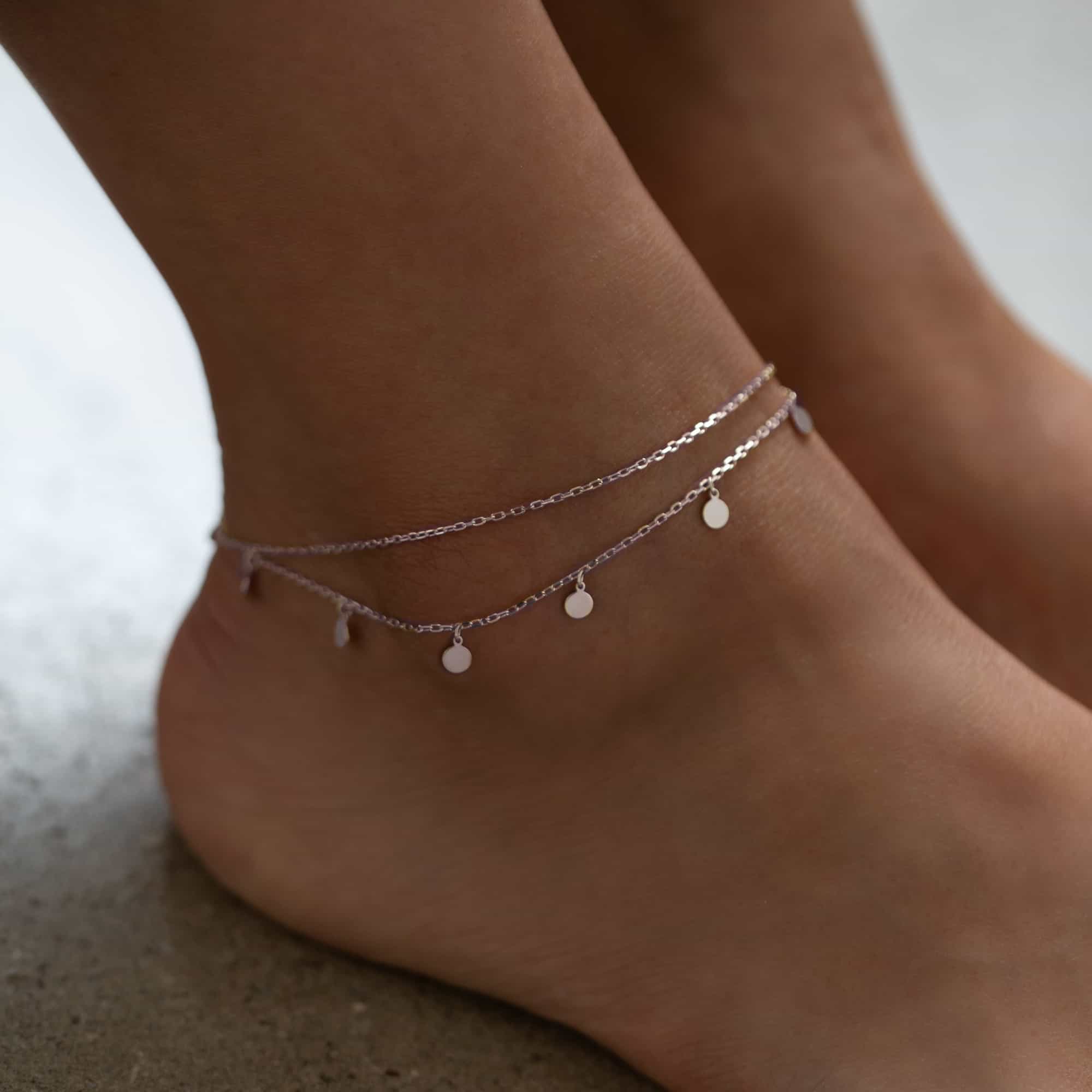 Sterling silver double-chain disc anklet shown close-up on a model's ankle