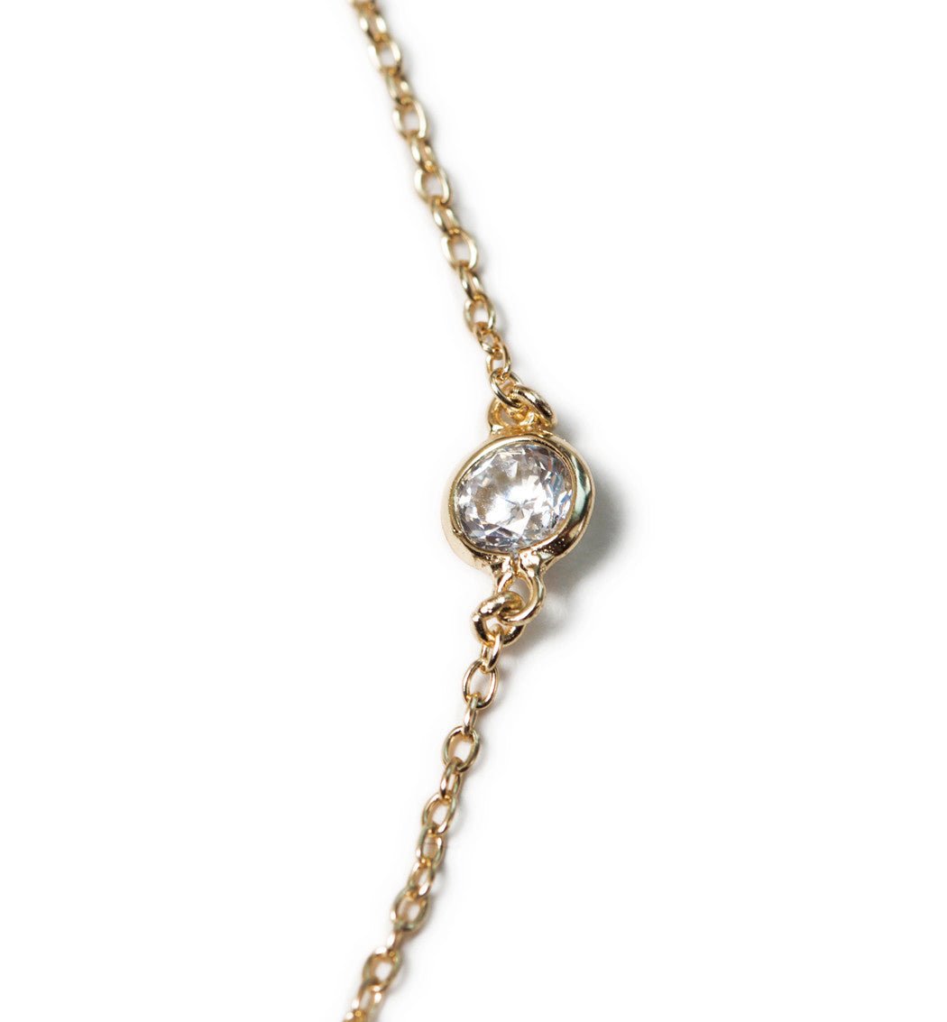 Close-up detail of a round bezel-set clear stone on a fine silver chain anklet