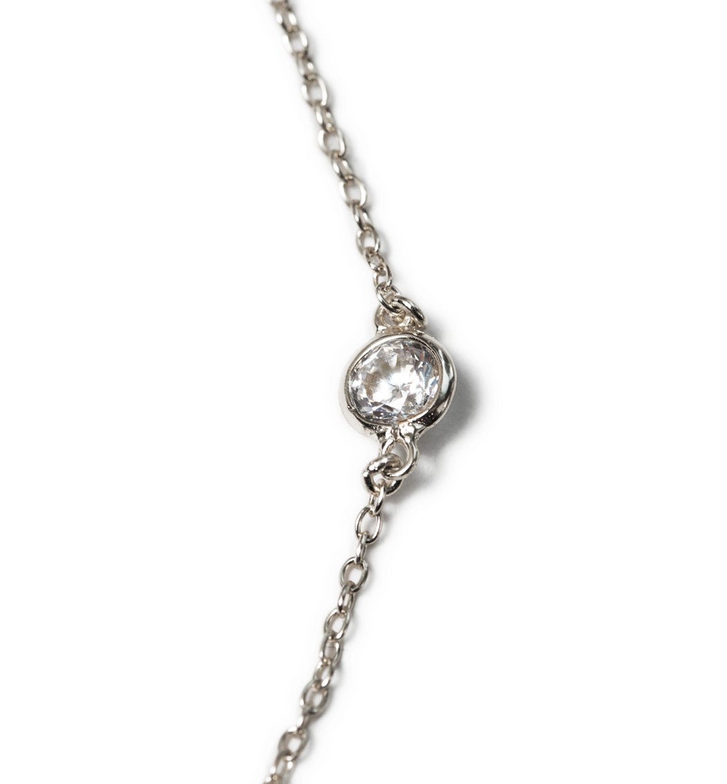 Sterling silver station anklet, close-up detail of a round bezel-set clear stone on the chain