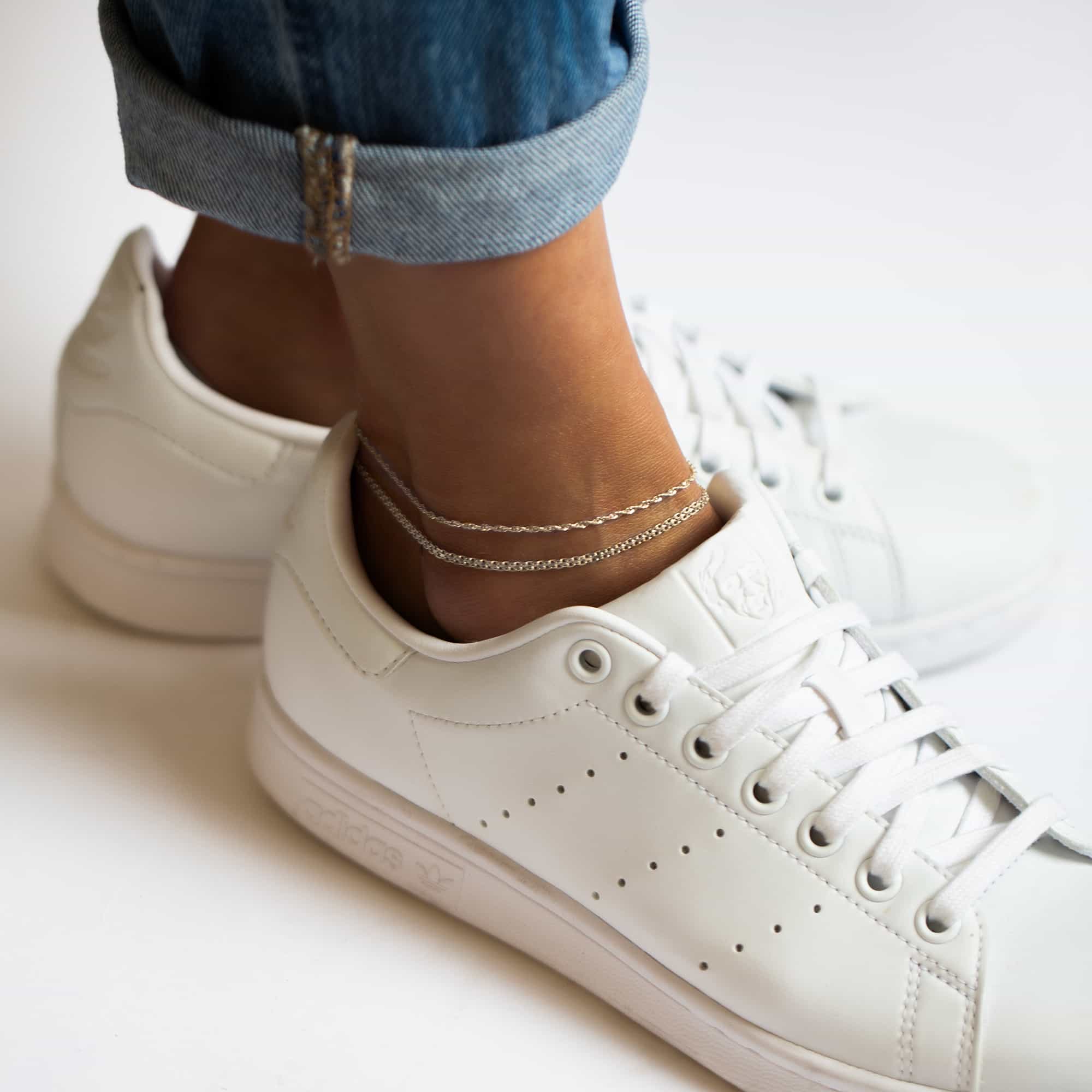 Sterling silver Bismark chain anklet layered on a model's ankle above a white sneaker