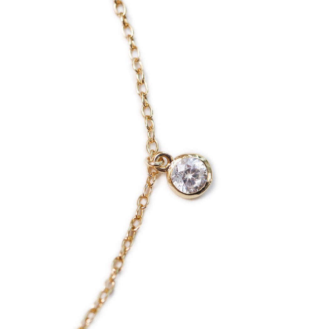 Gold vermeil anklet close-up showing a single bezel-set round clear stone drop on a fine chain