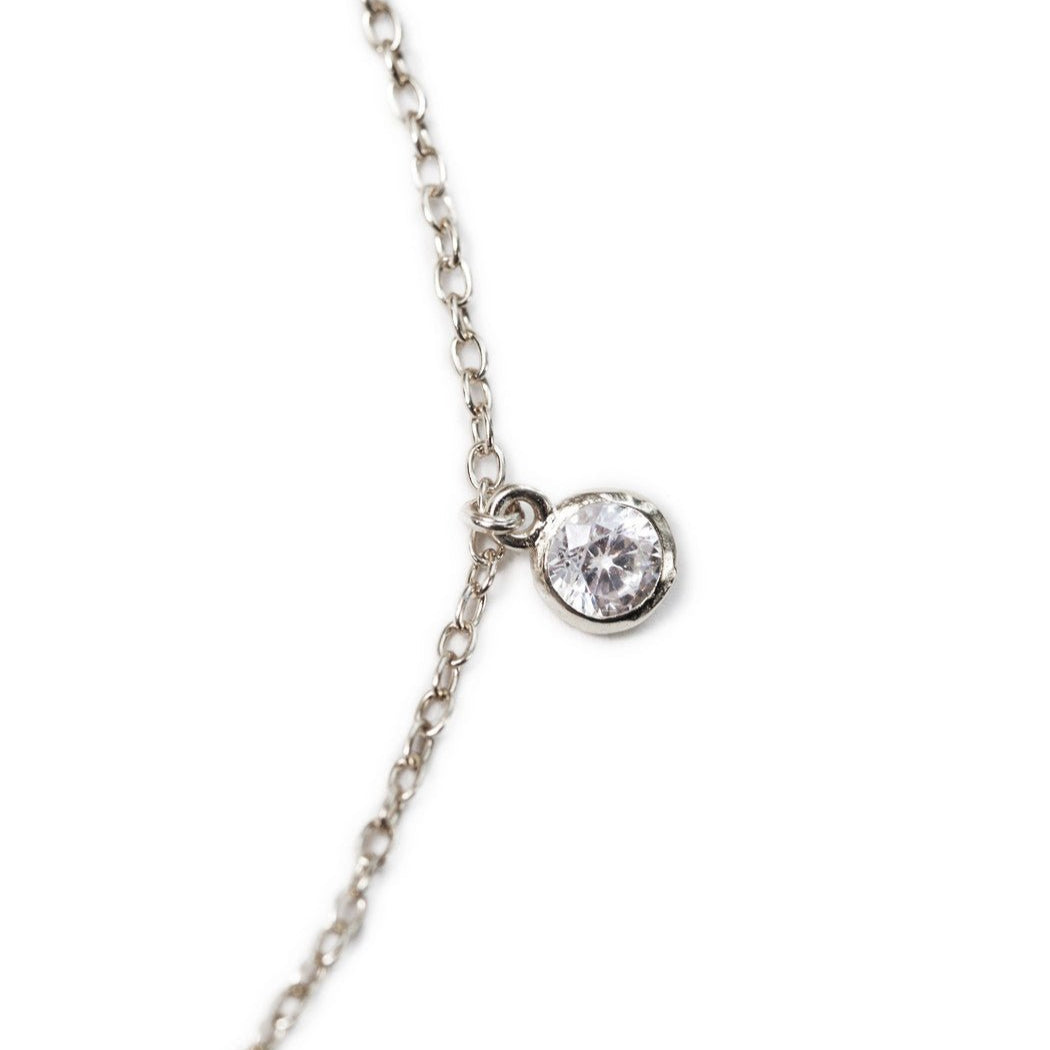 Sterling silver anklet close-up showing a single bezel-set round clear stone drop on a fine chain