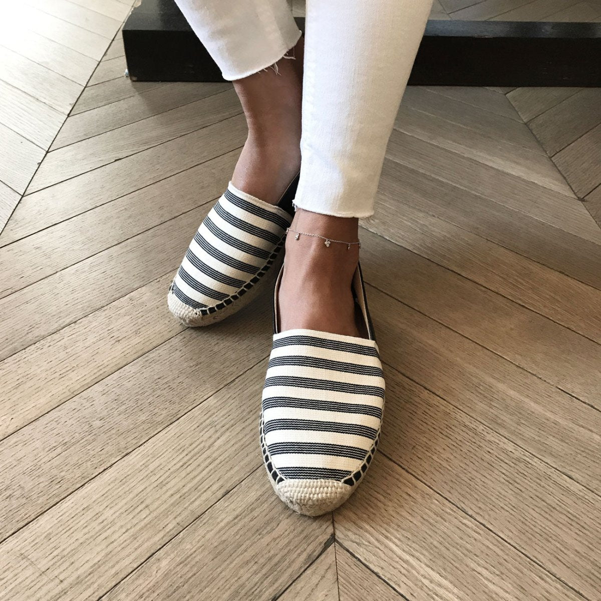 Sterling silver clover anklet with tiny clear stones, shown on a model's ankle with striped espadrilles