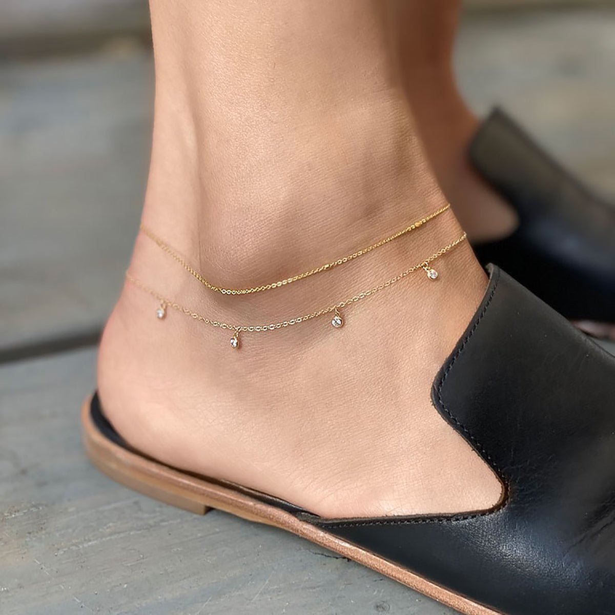 Gold vermeil layered anklets with small clear stone drops, shown on a model's ankle