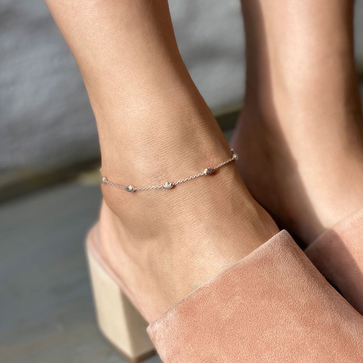 Sterling silver faceted oval bead anklet shown on a model's ankle with a pink heeled mule