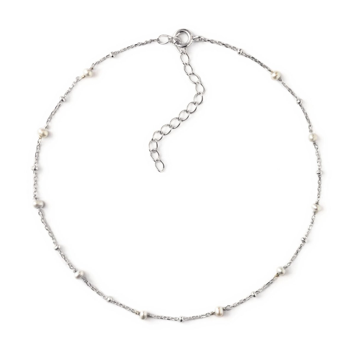 Sterling silver beaded chain anklet with small pearl stations, laid in a circle on a white background