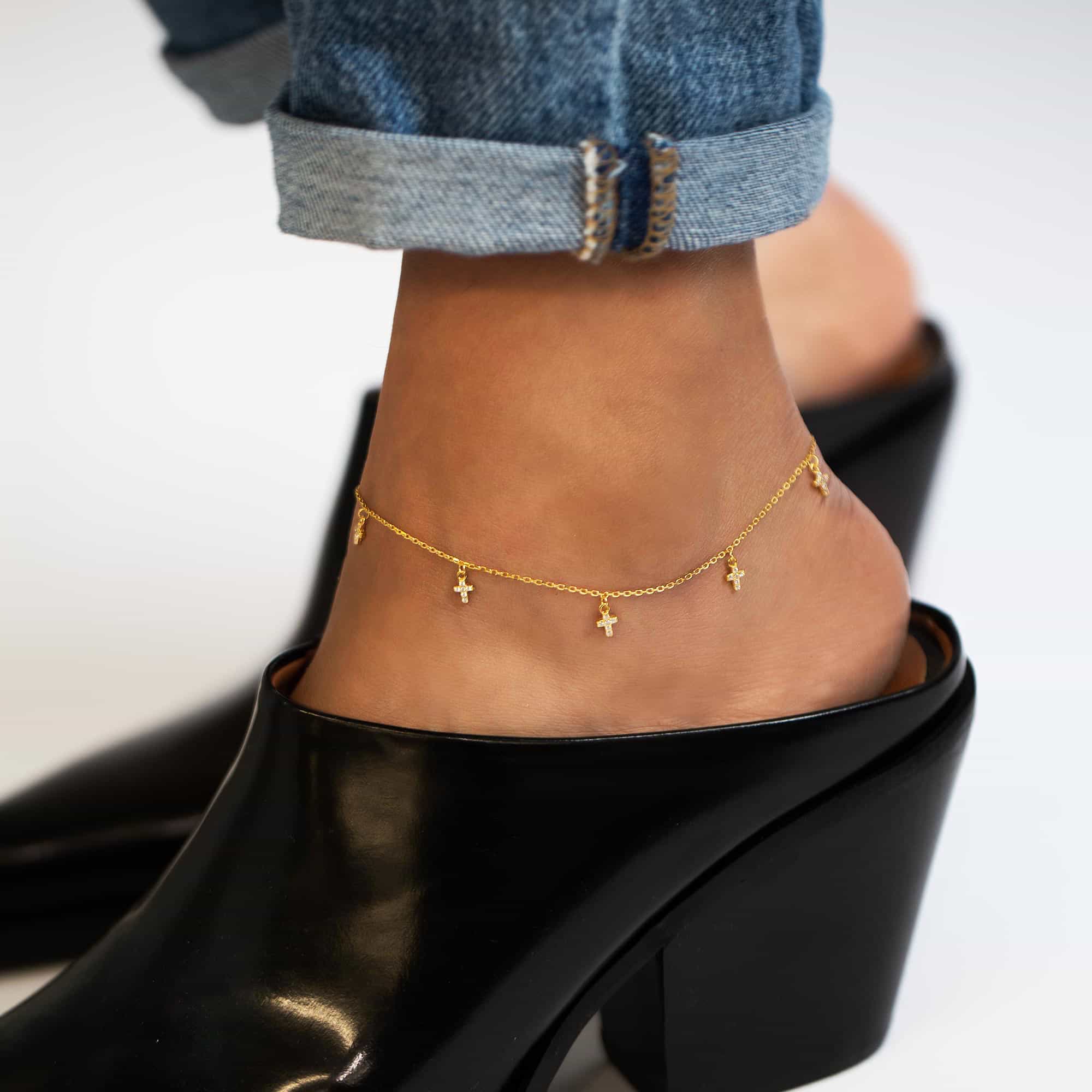 Gold vermeil pavé zirconia cross-charm anklet shown on a model's ankle with denim and heels