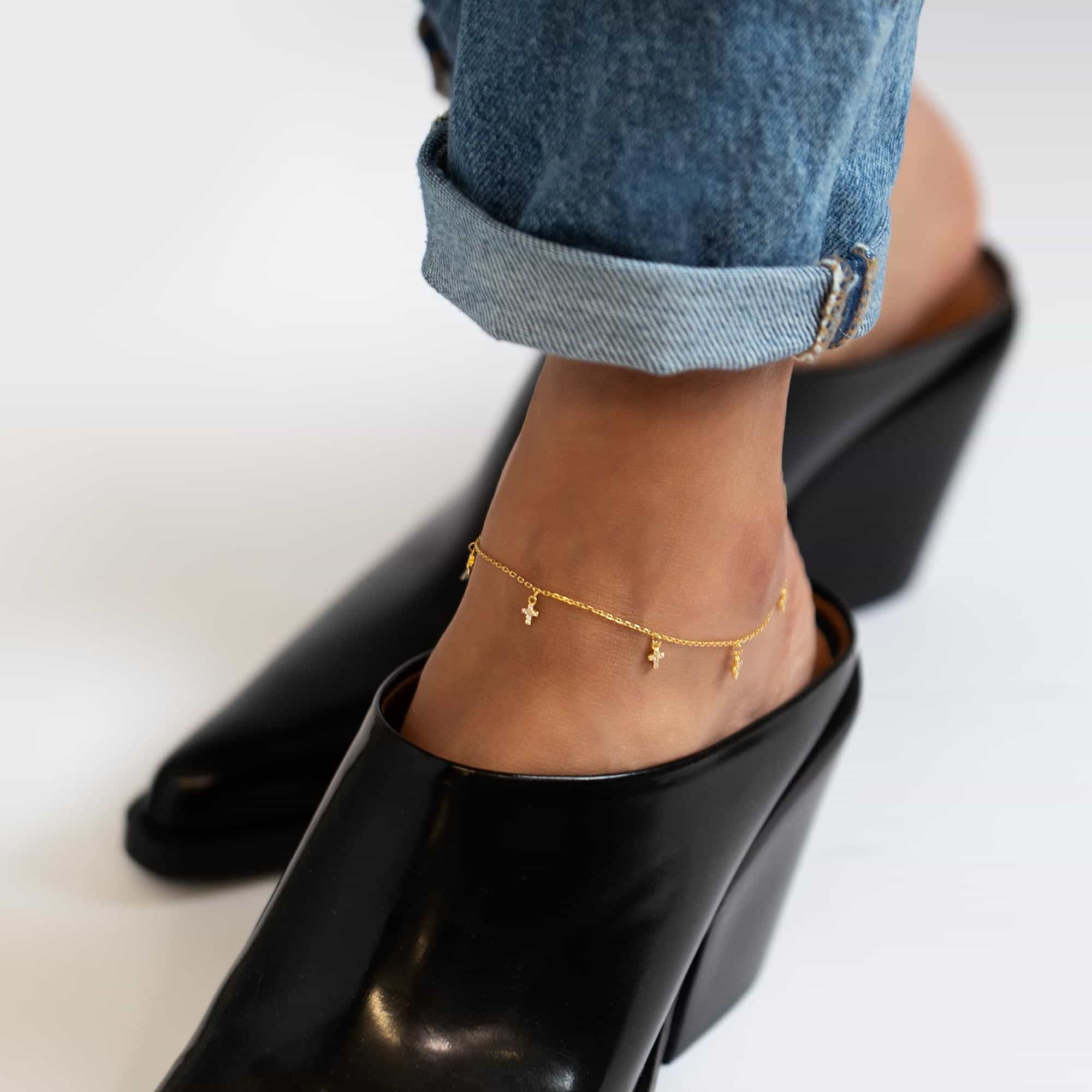 Gold vermeil anklet with dangling tiny crystal-set crosses, shown on a model's ankle above a black heel