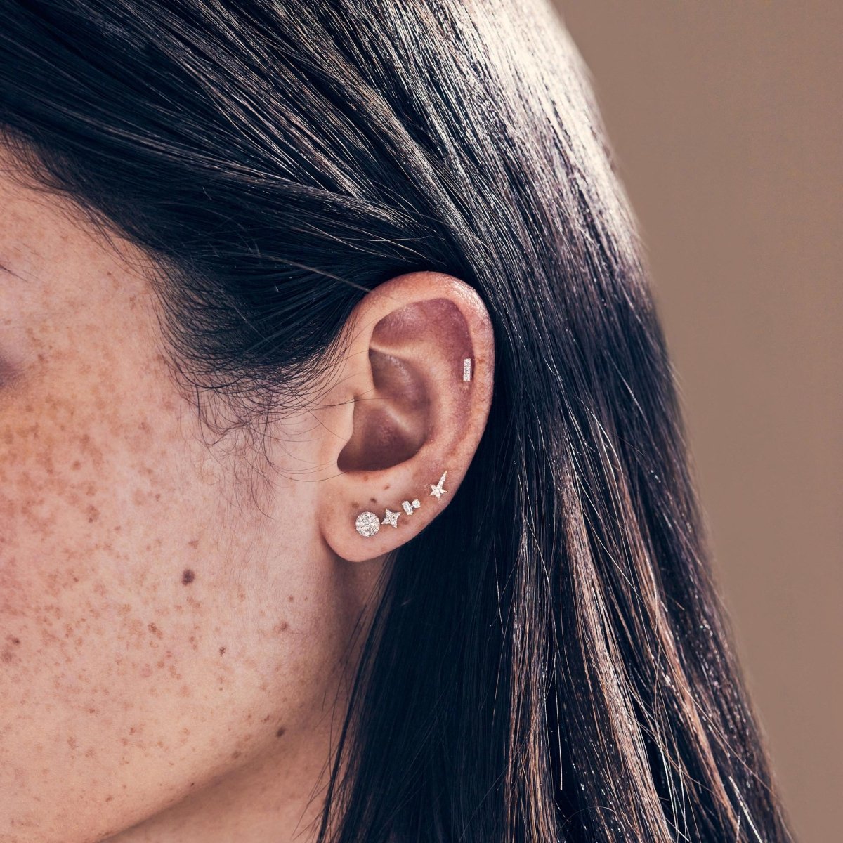 14K white gold baguette and round diamond duet studs shown on a model's upper lobe