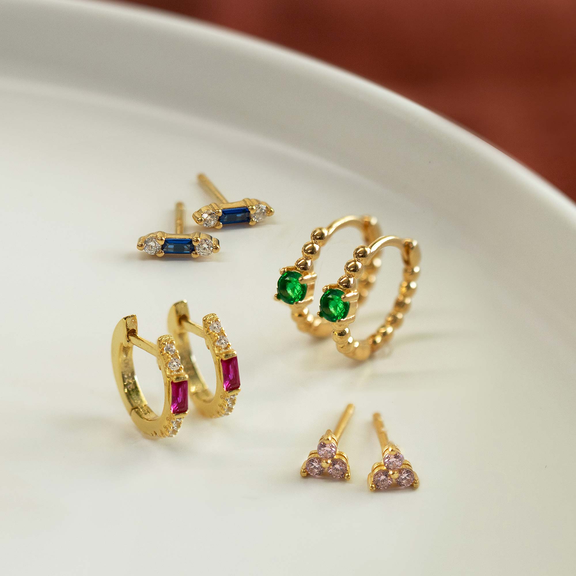 Close-up on earring featuring Gold Vermeil Gemstone Bead Huggies Emerald CZ Crystal and other gemstone earrings. 