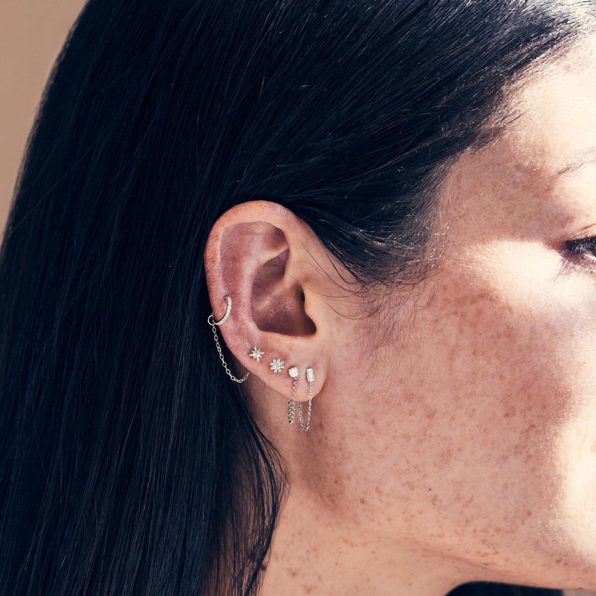 14K white gold diamond chain stud earring shown on a model's ear in a curated stack
