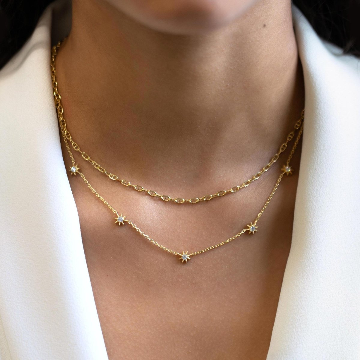 Gold vermeil Marina chain and starburst station necklaces with white zirconia, shown on a model's neckline