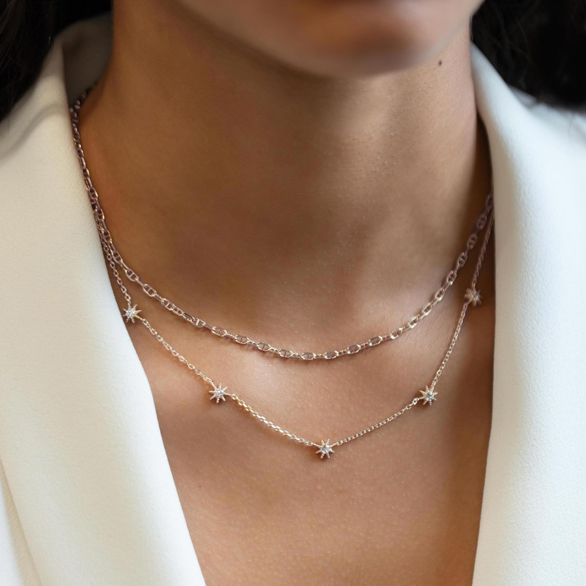 Sterling silver Marina chain choker layered with a gold star station chain, shown on a model's neckline