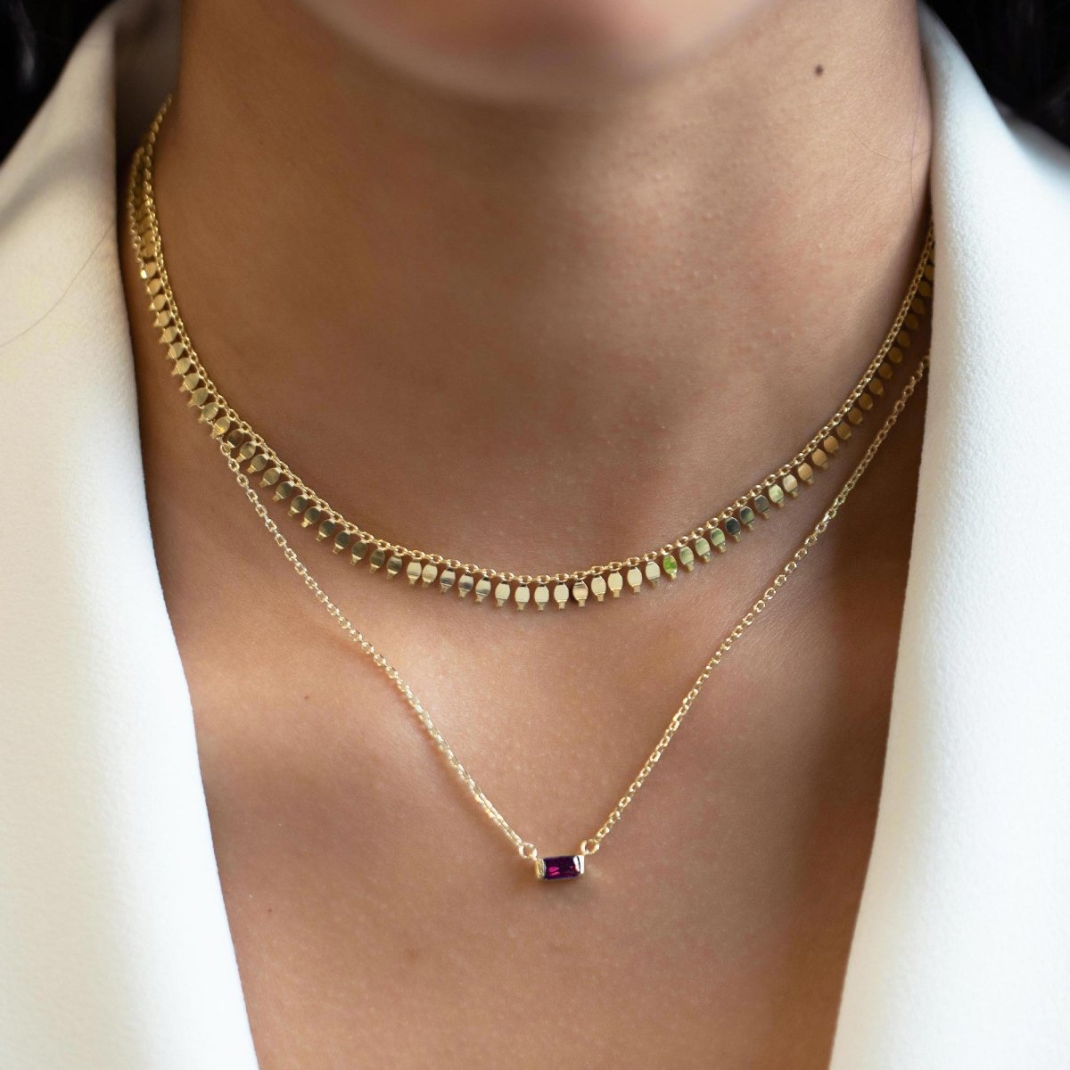 Gold vermeil layered necklaces with a ruby baguette pendant, shown on a model's neck